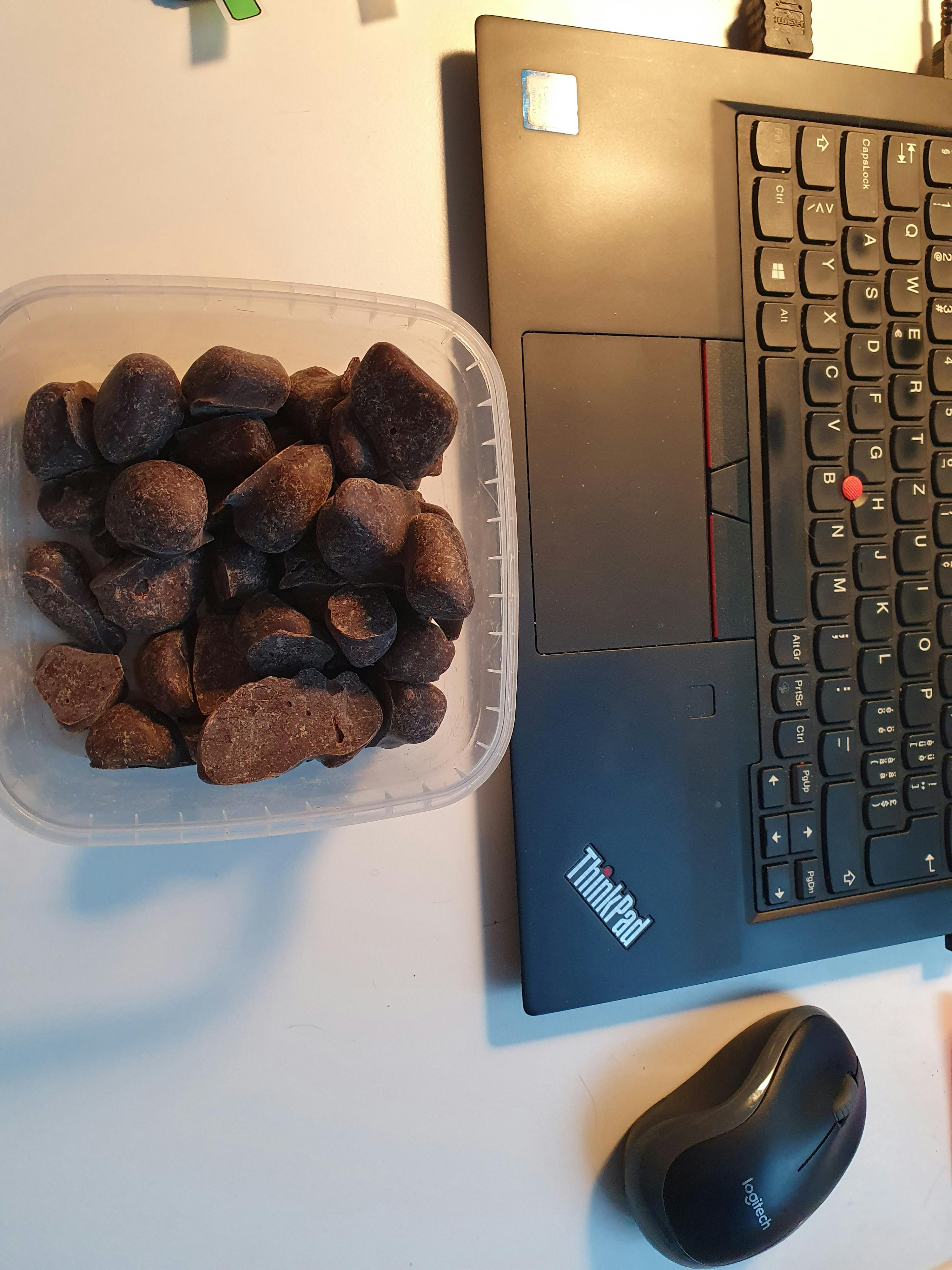 a container of chocolate sits in front of a thinkpad laptop