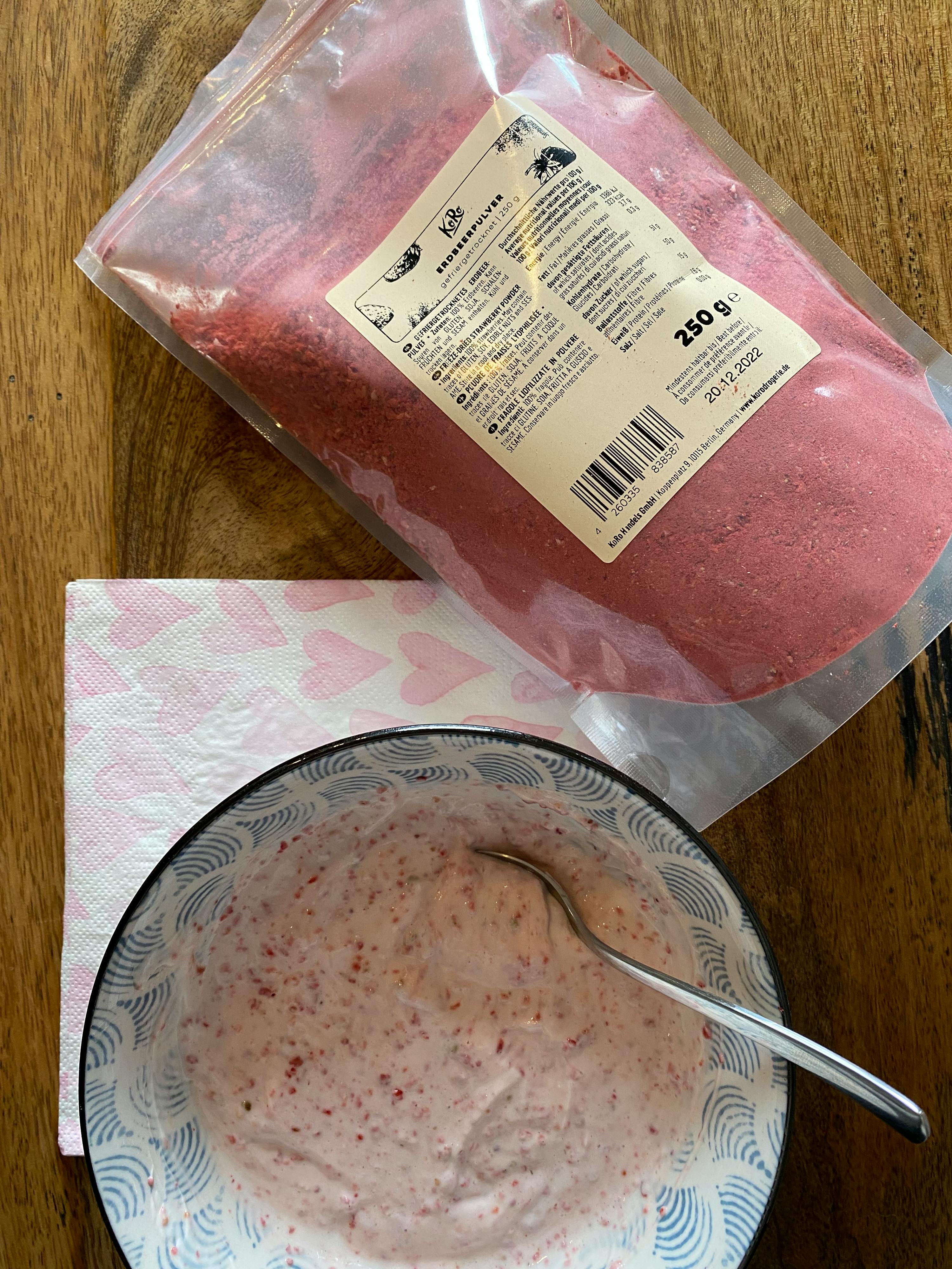 eine Schüssel mit Erdbeerpüree neben einem Plastikbeutel mit 250 g Erdbeerpulver