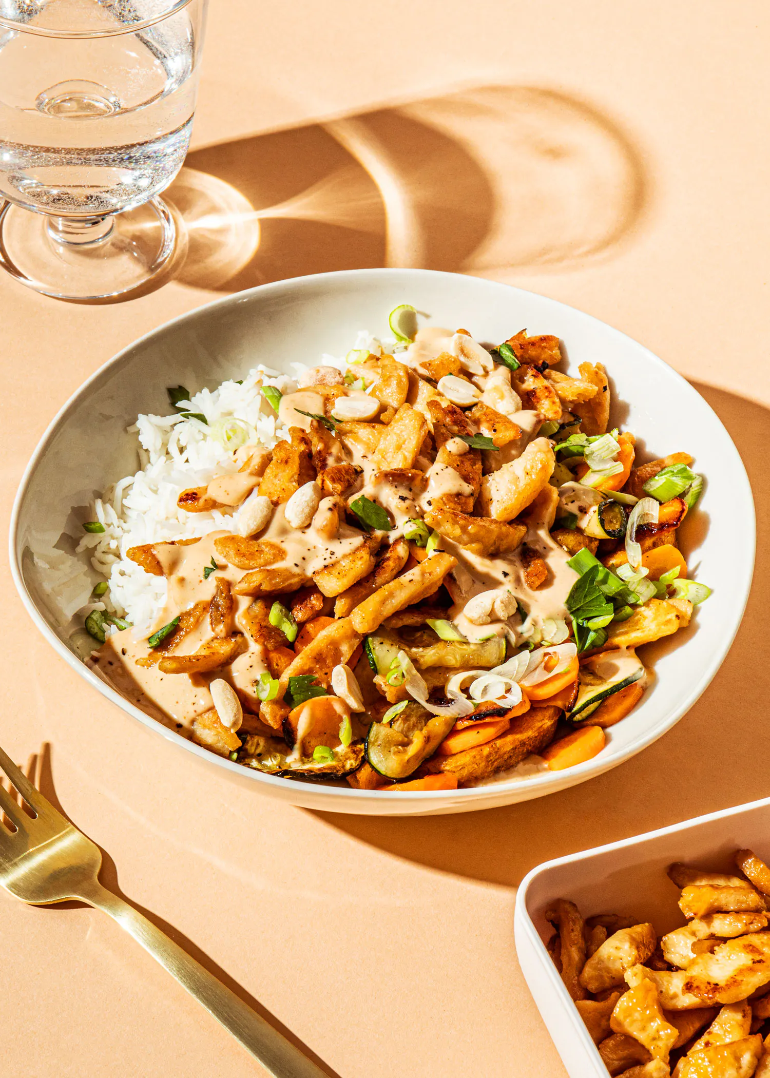un plato de comida con arroz y verduras junto a un vaso de agua y un tenedor