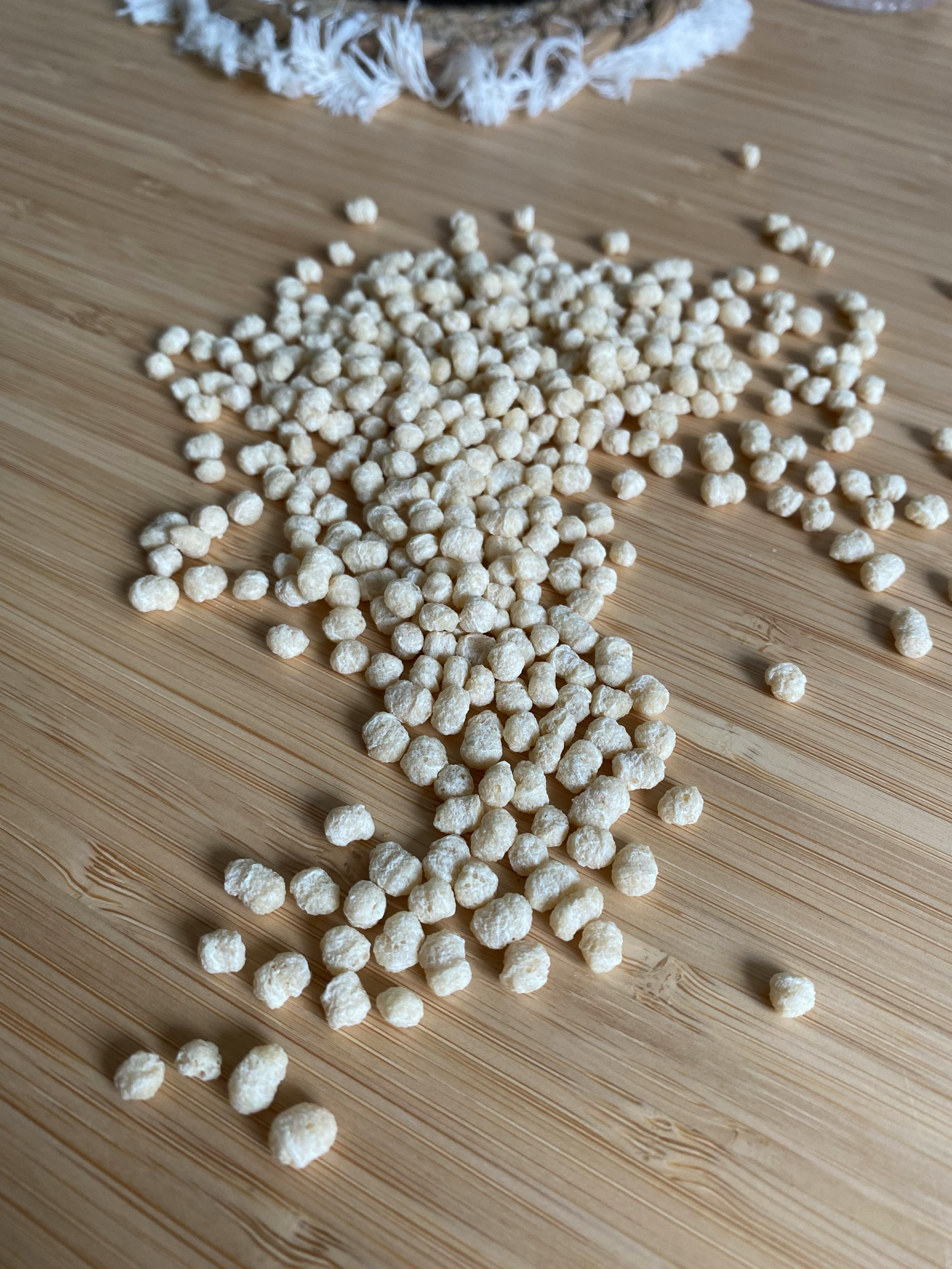 un mucchio di piccole perle bianche su un tavolo di legno
