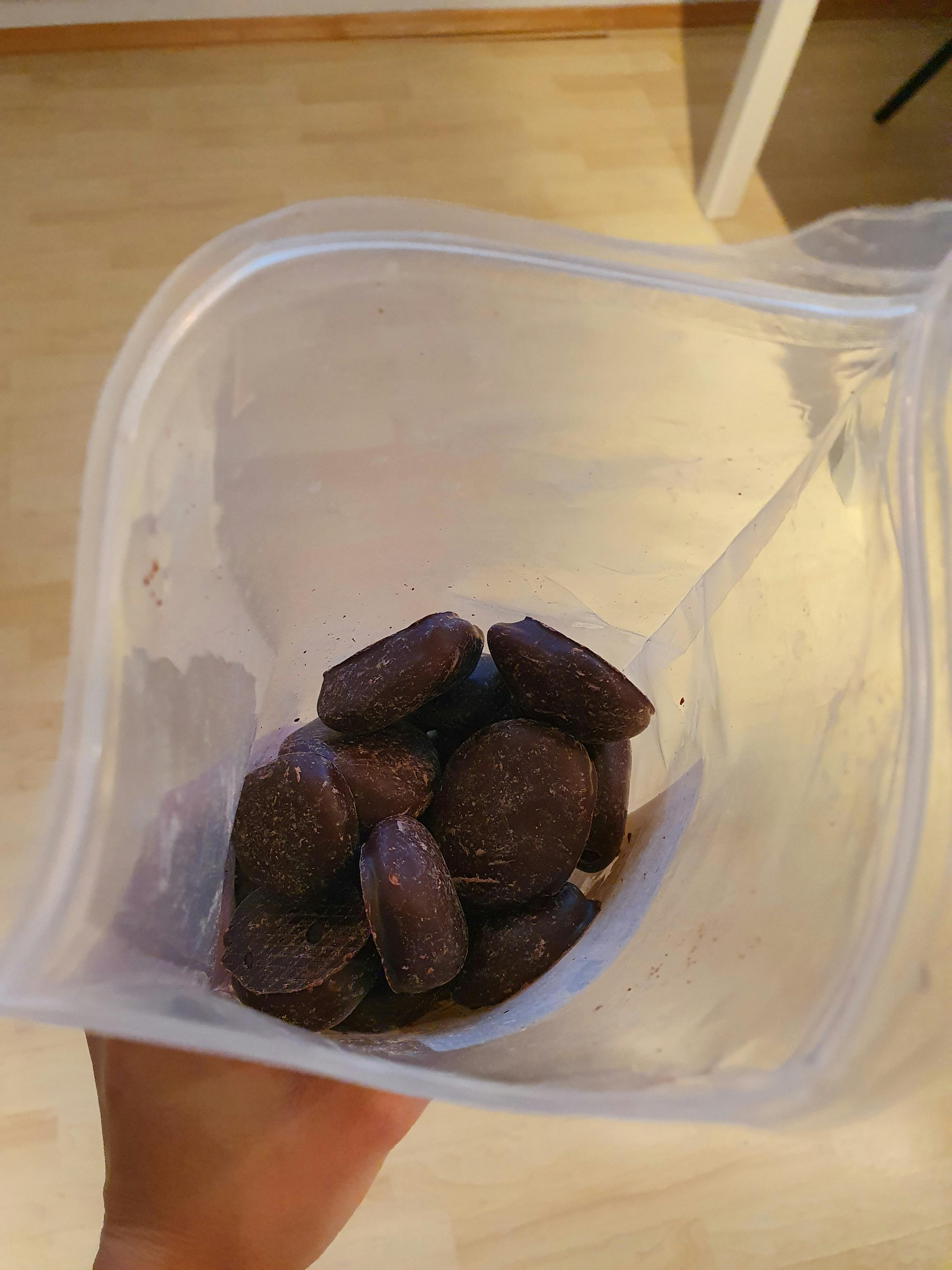 eine Person hält einen Plastikbeutel mit Schokoladenstückchen darin