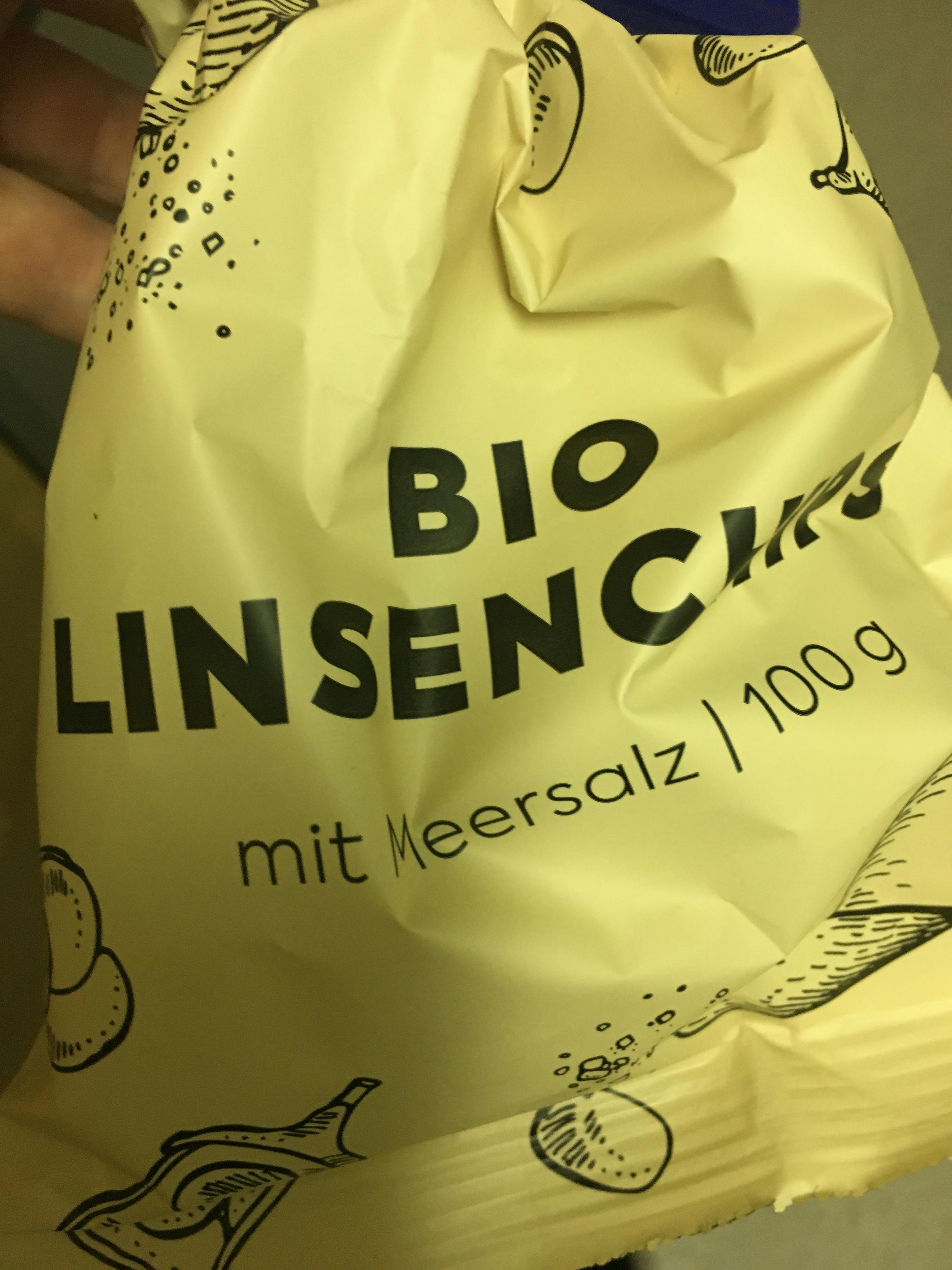 Eine Person hält eine Tüte Linsenchips mit Meersalz