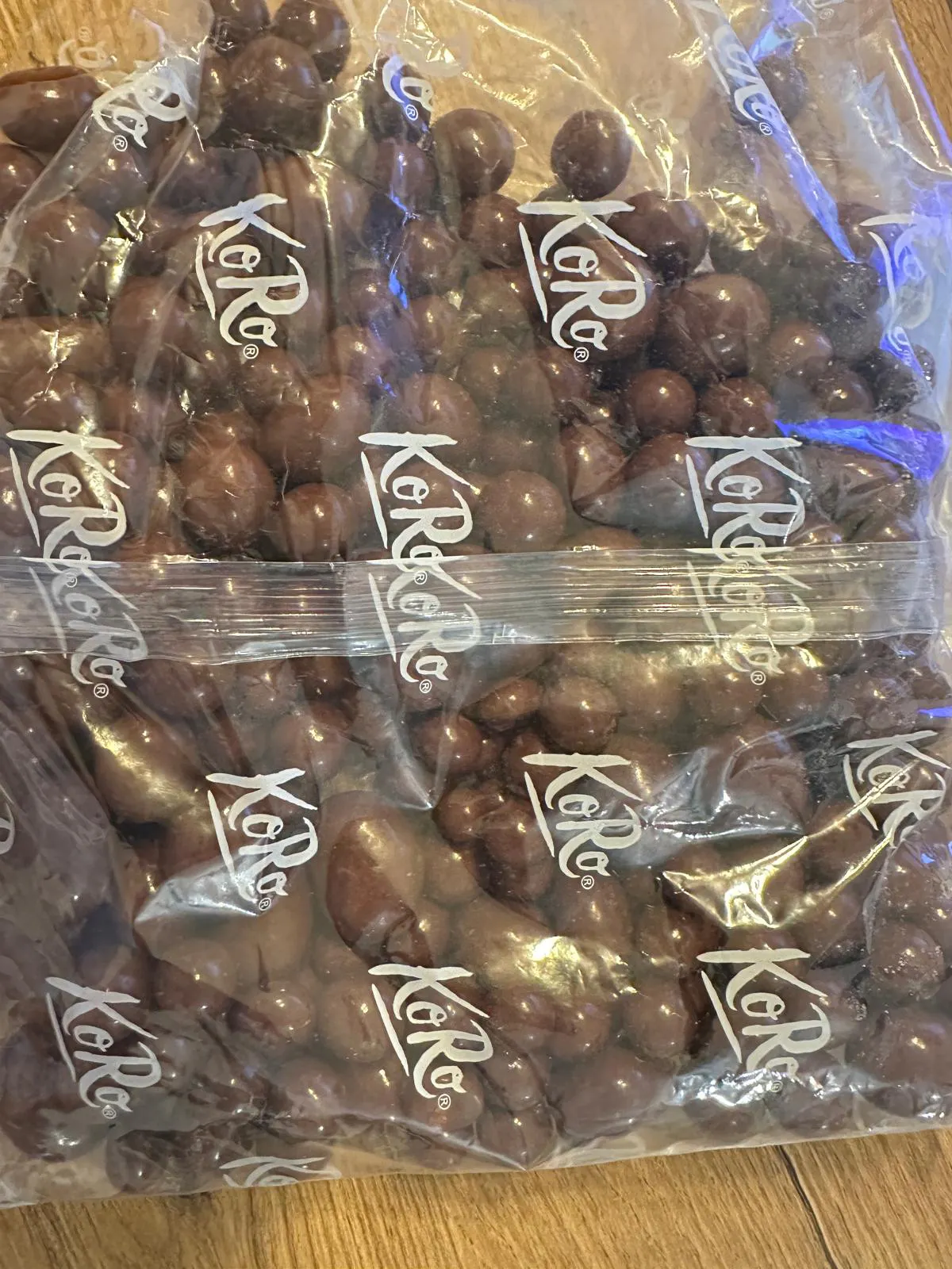 sacchetto di plastica trasparente contenente palline di cioccolato con il logo koro stampato ripetutamente sulla superficie.