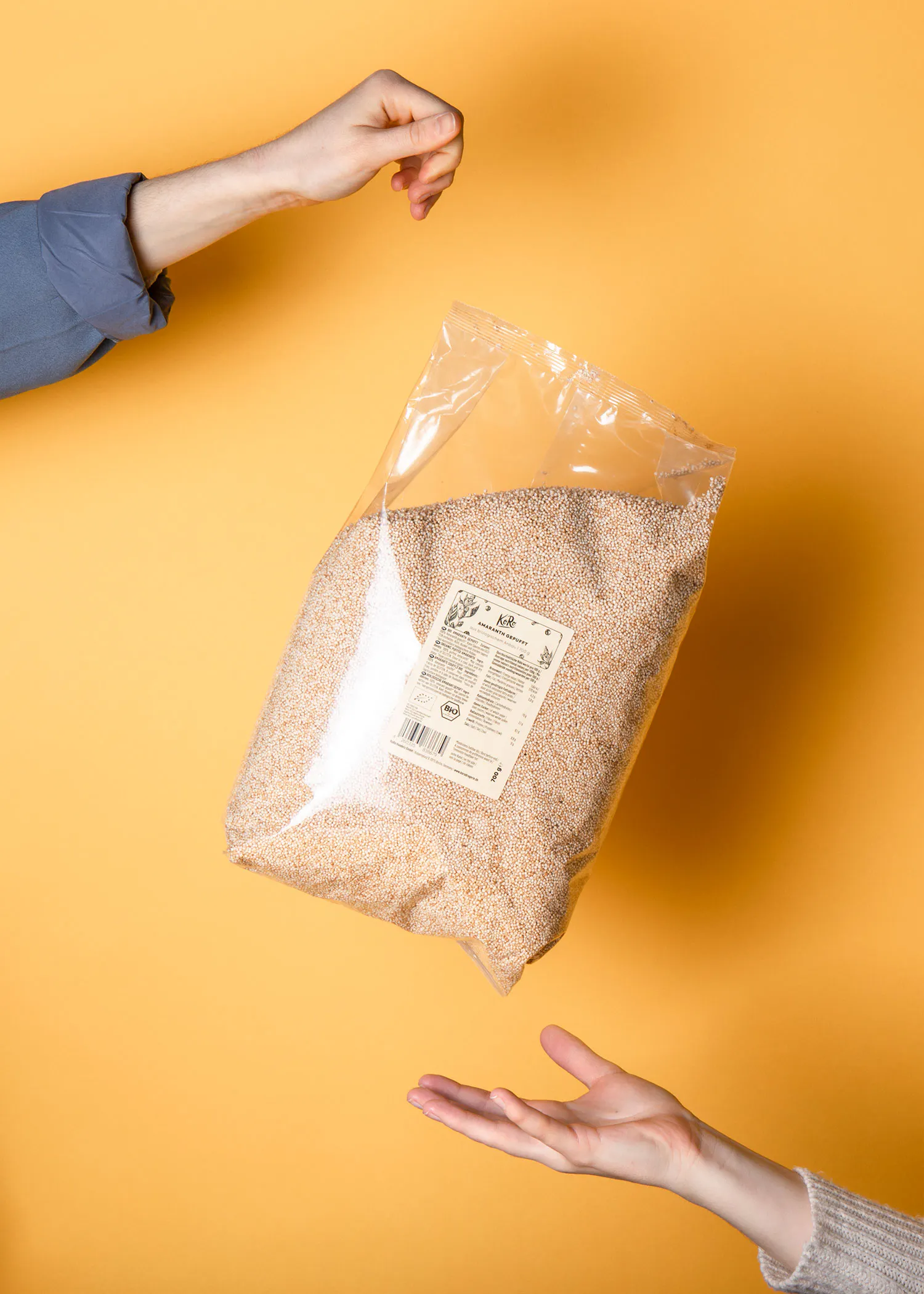 deux mains tenant un sac de graines de quinoa