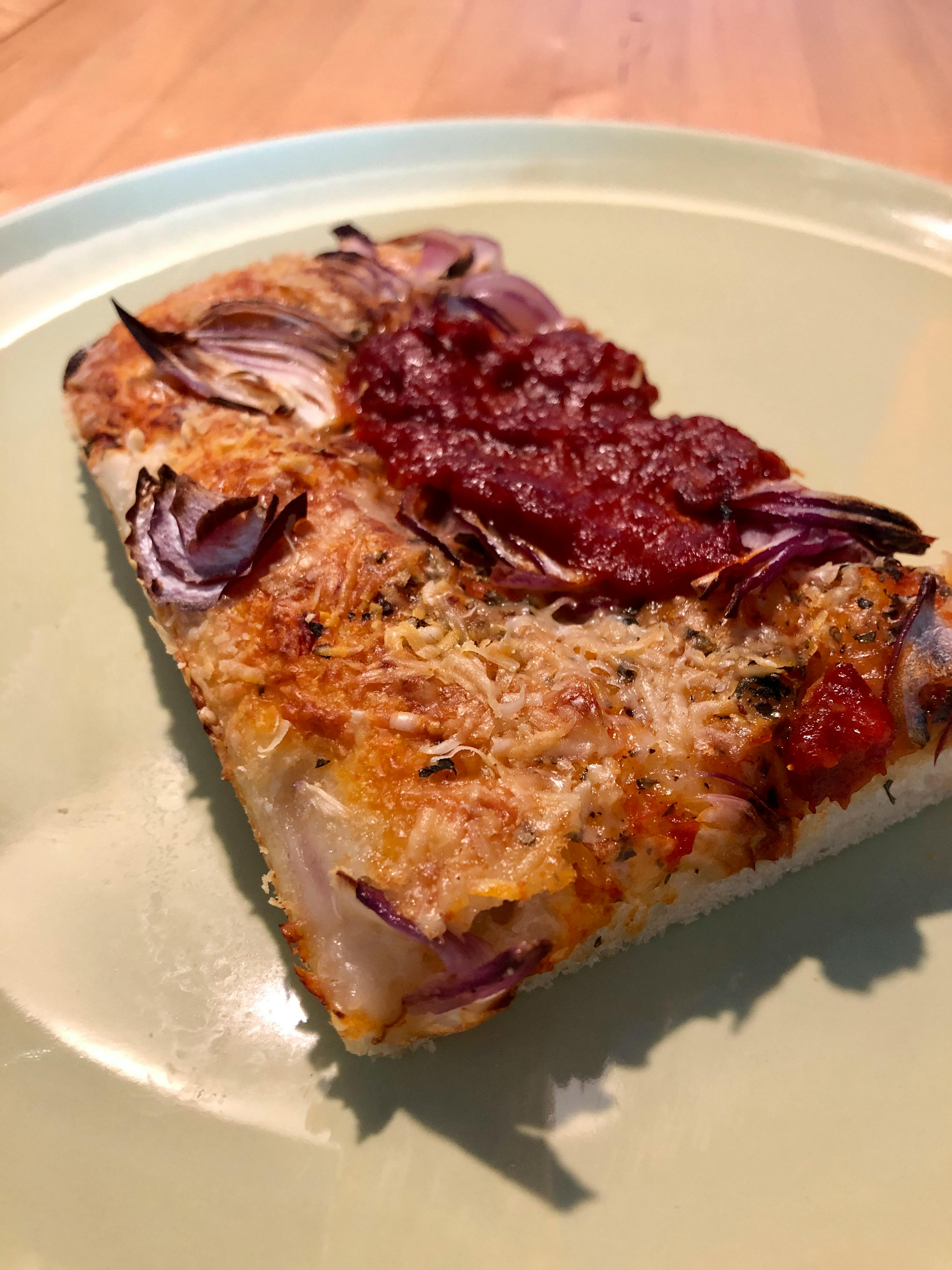 une pizza avec des oignons et de la sauce sur une assiette verte