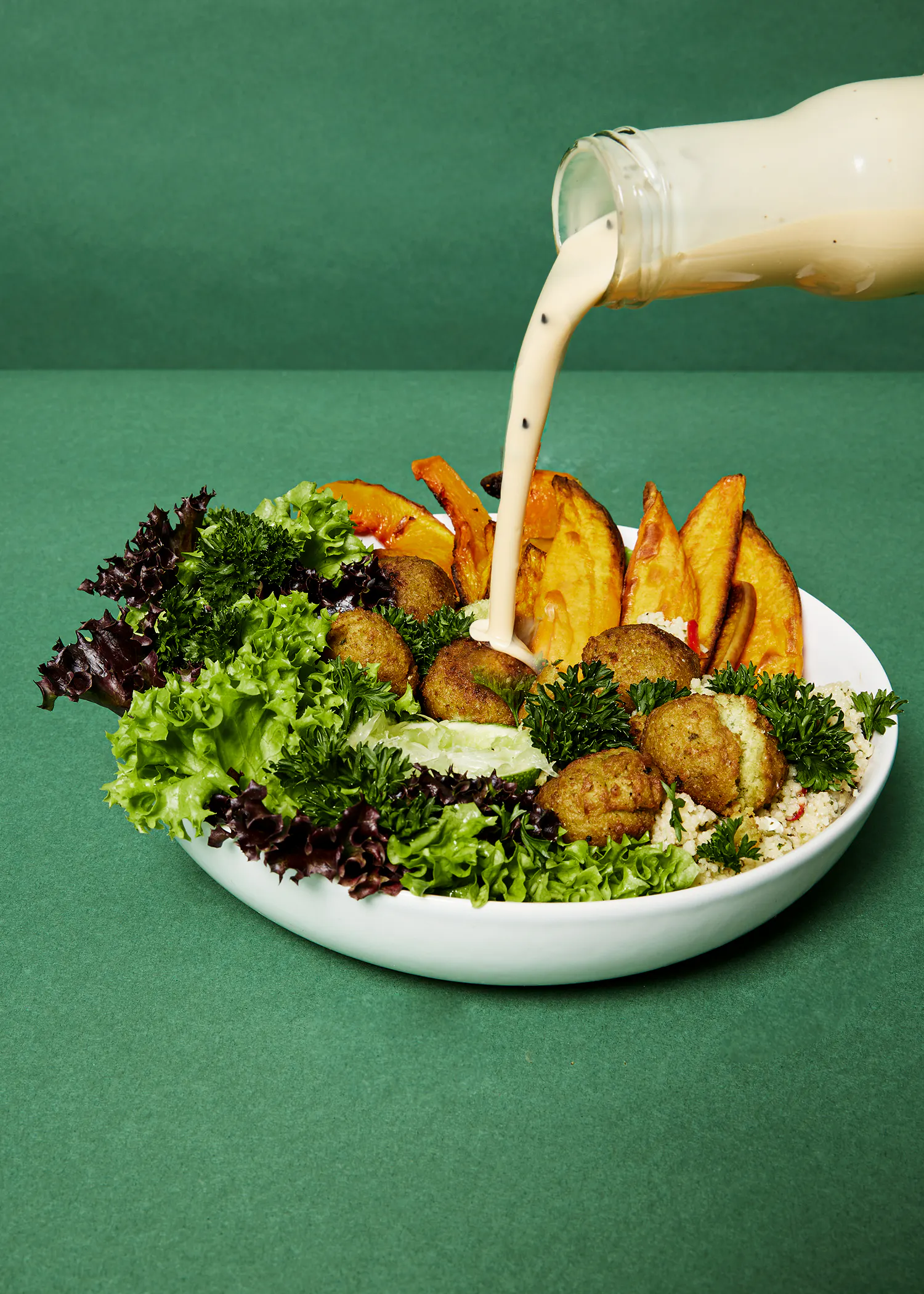 una ensalada con falafel y papas fritas se sirve en un plato blanco