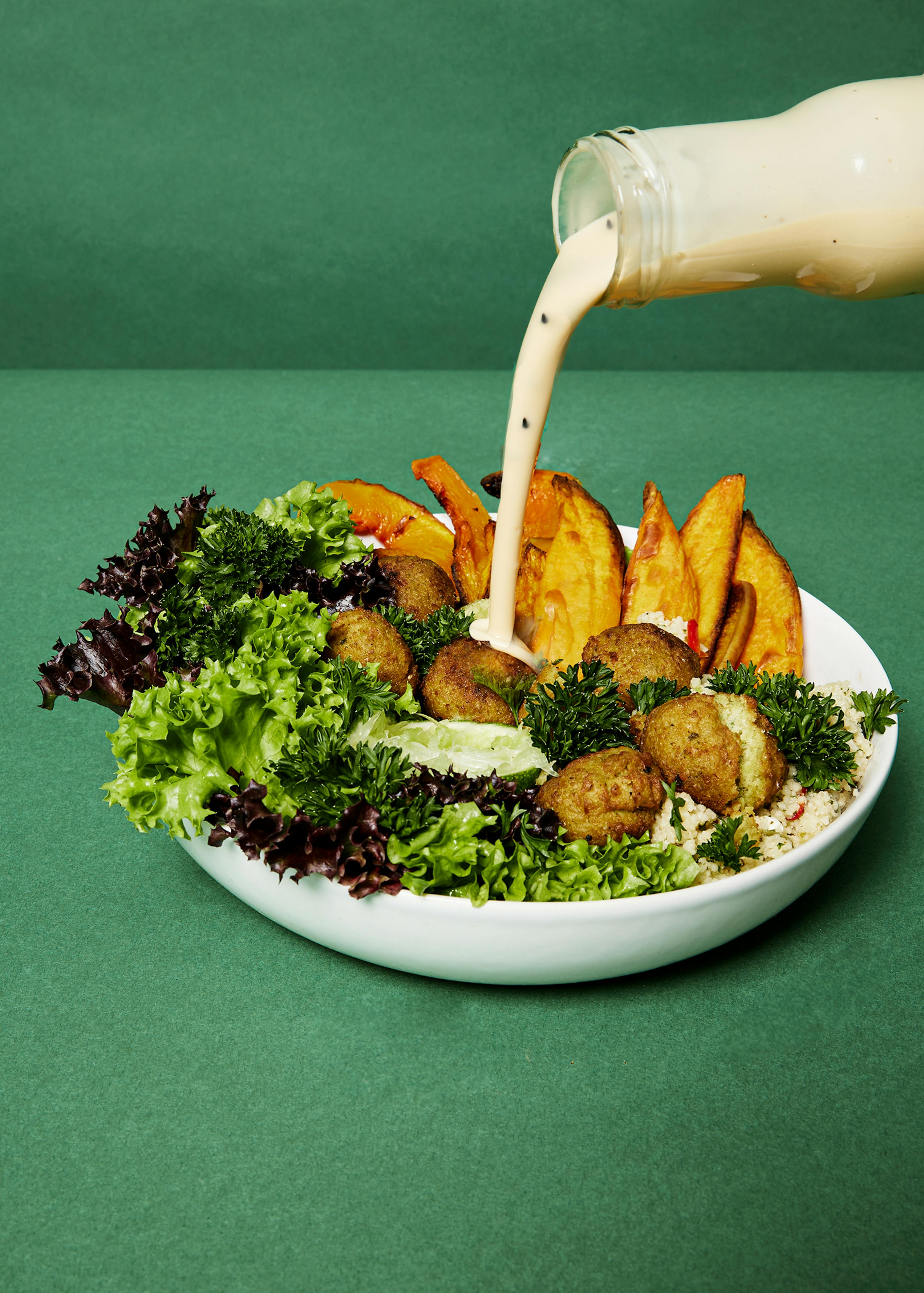 eine Flasche Soße wird über einen Teller mit Essen gegossen