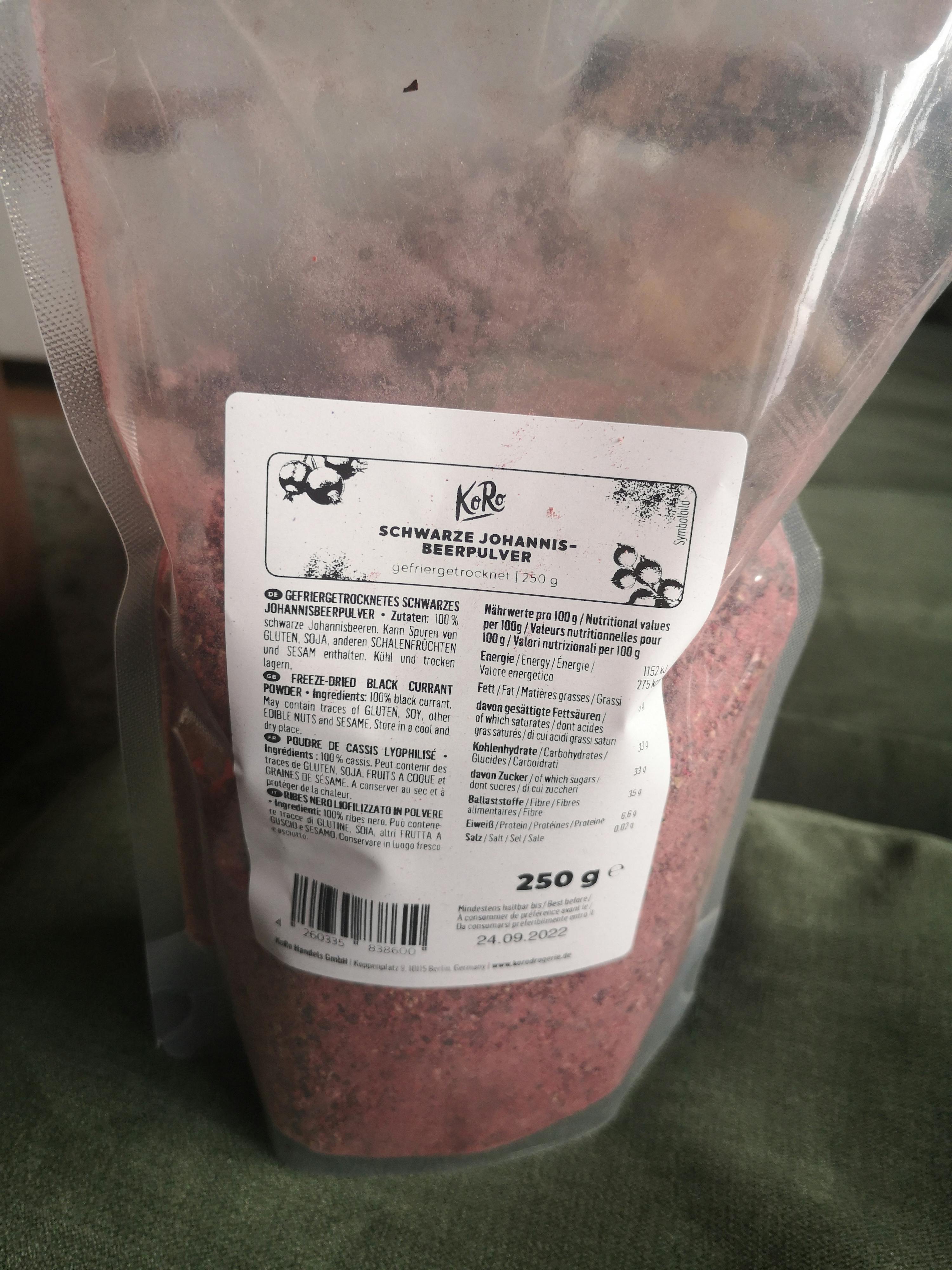 eine verpackte schwarze johannisbeerpulver liegt auf einem grünen tisch