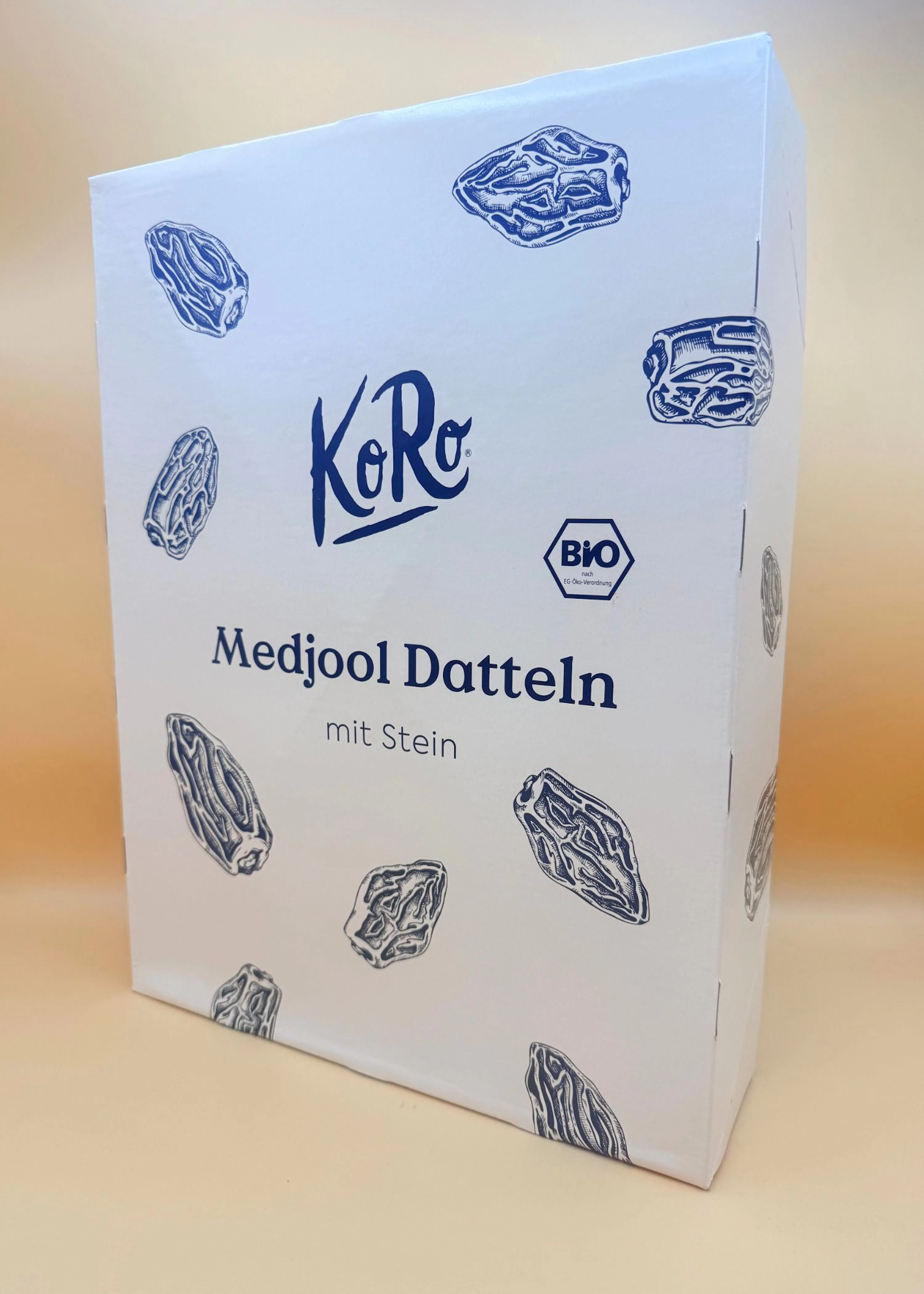 weiße koro-schachtel mit medjool-datteln mit stein, verziert mit dattelillustrationen und einem bio-logo.