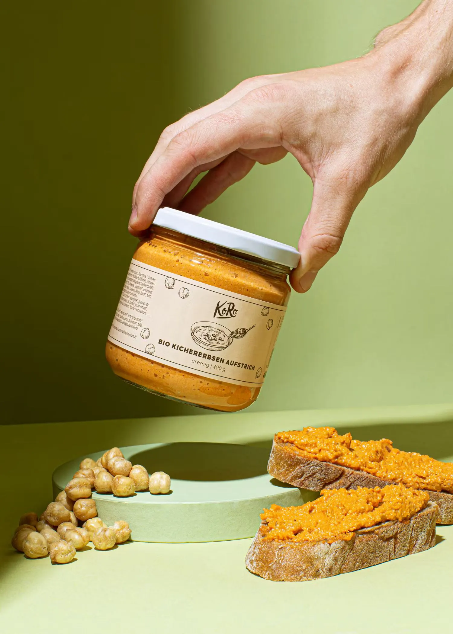 a person is holding a jar of bio kichererbsen aufstrich