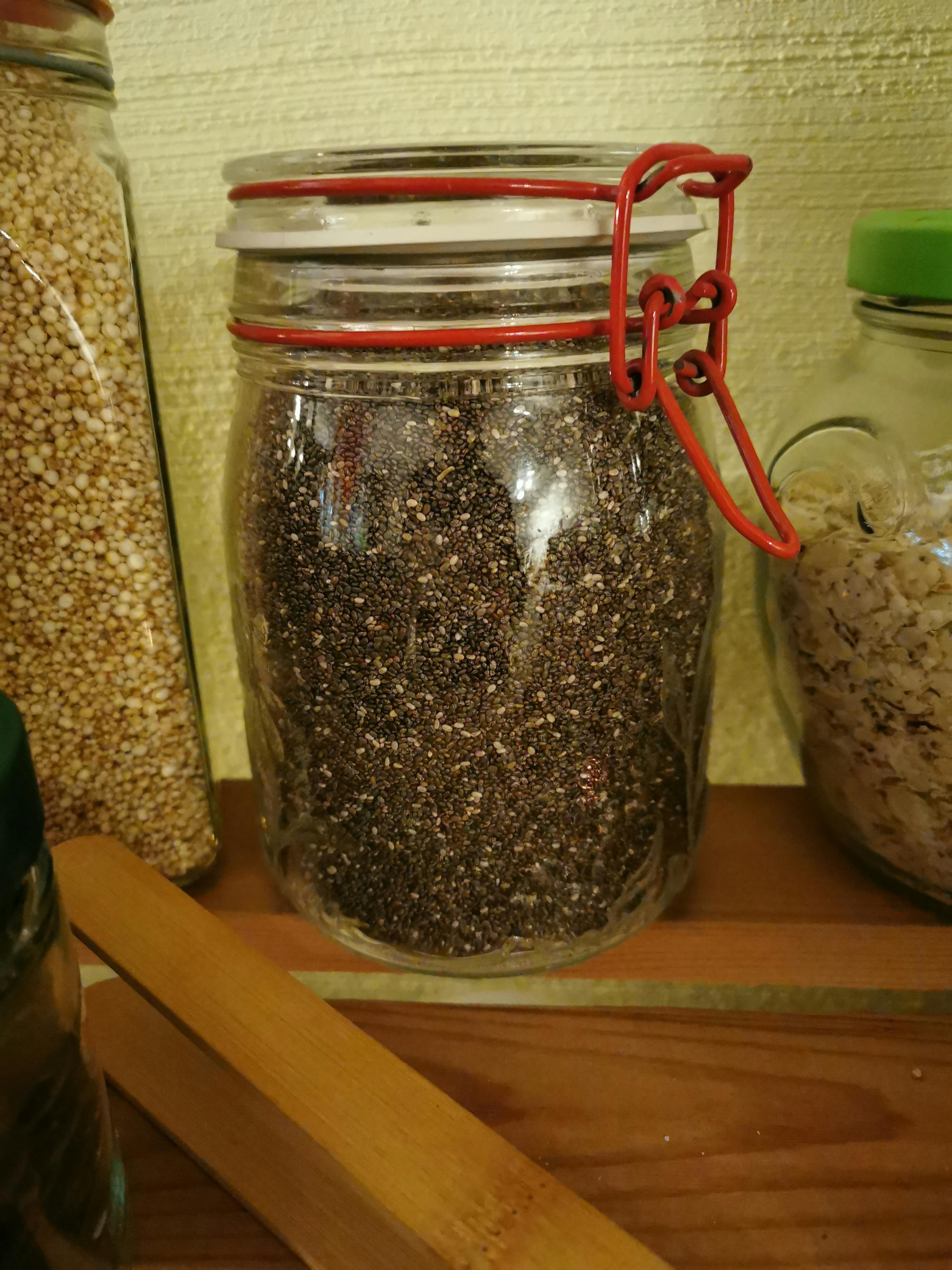 a jar filled with chia seeds sits on a wooden shelf