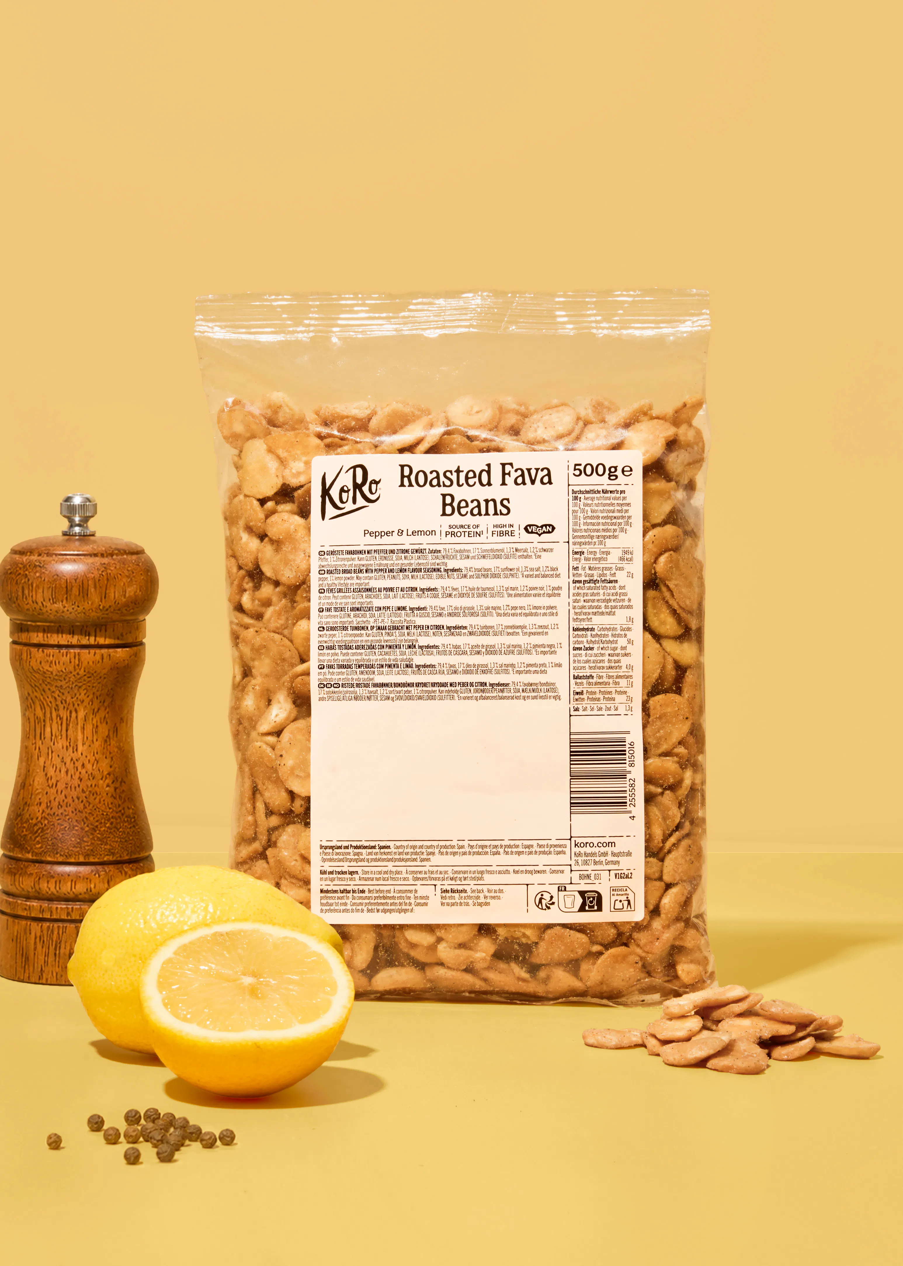 sachet de fèves grillées au poivre et au citron de la marque koro posé sur une table avec un moulin à poivre et un citron coupé en deux.