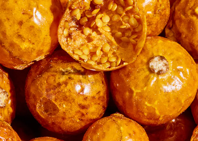 ein Haufen orangefarbener Früchte mit Samen darin