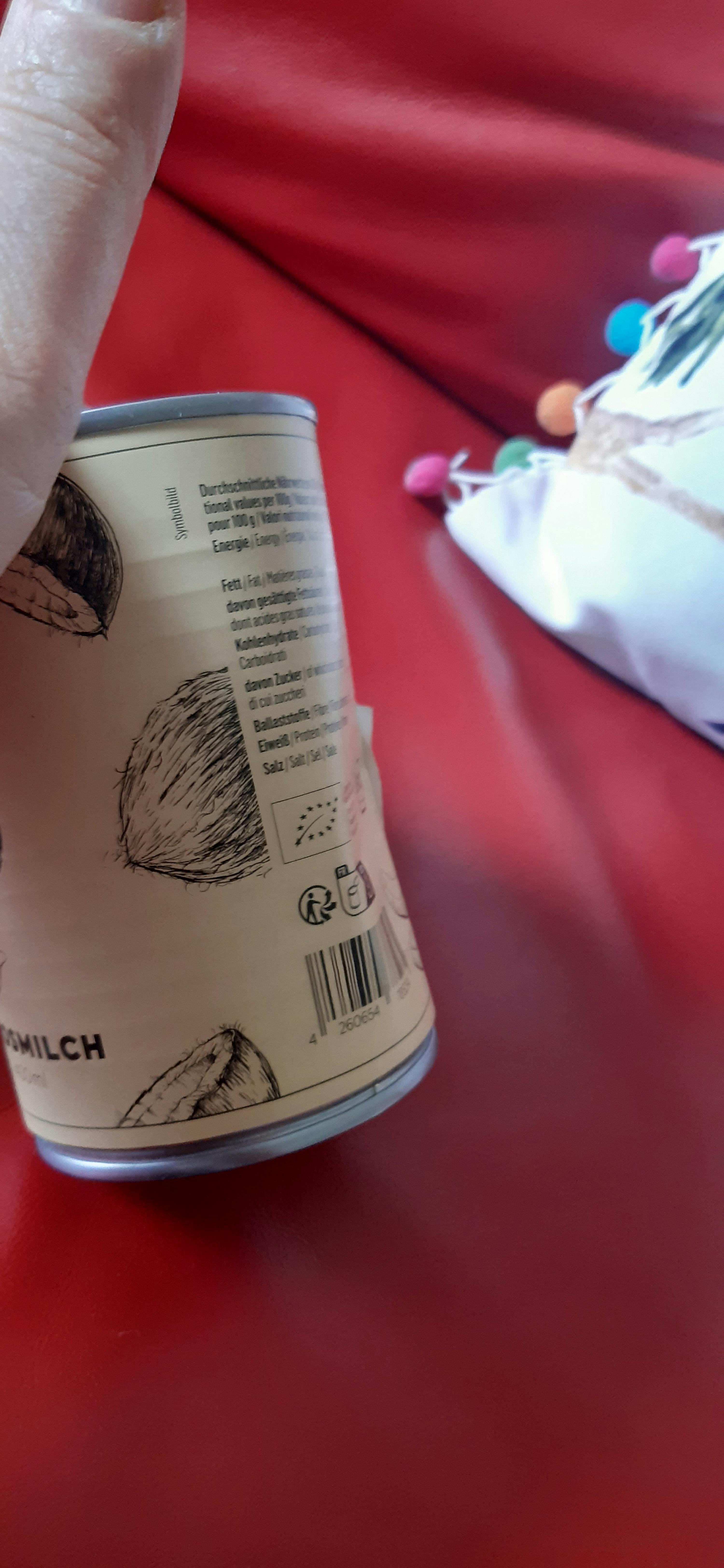 a hand is holding a can of coconut milk