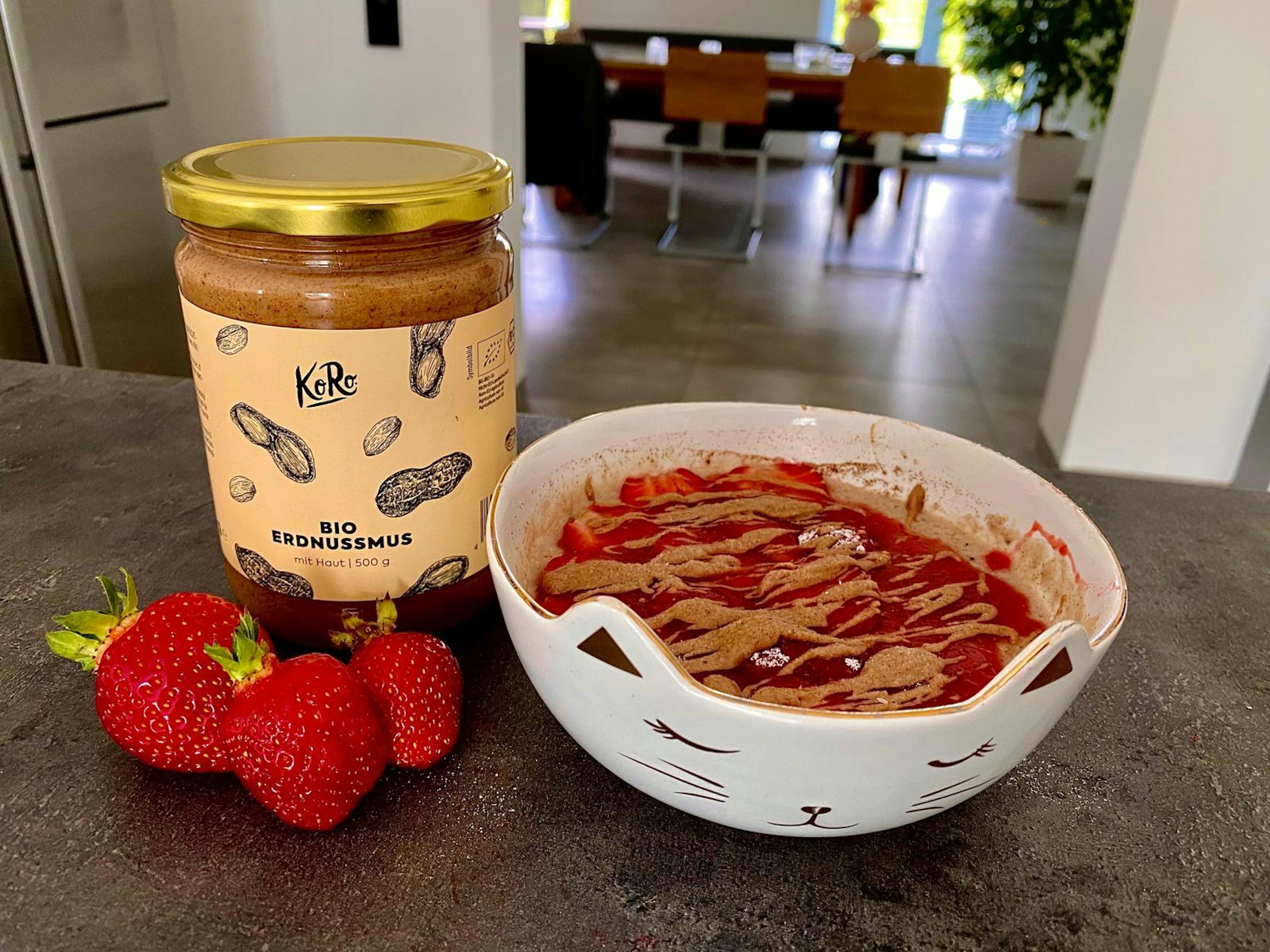 a jar of peanut butter next to a bowl of strawberries