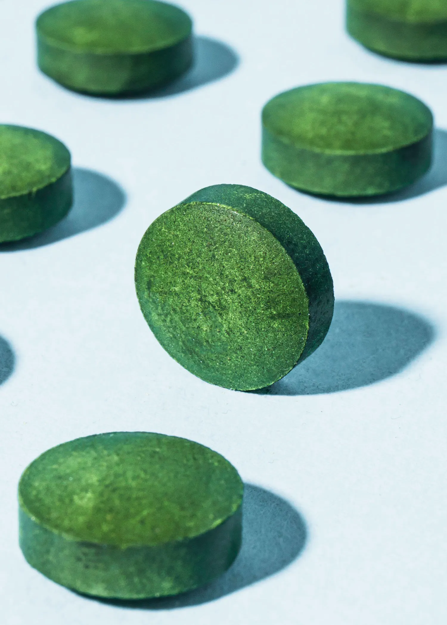 un groupe de pilules vertes sont assises sur une surface blanche