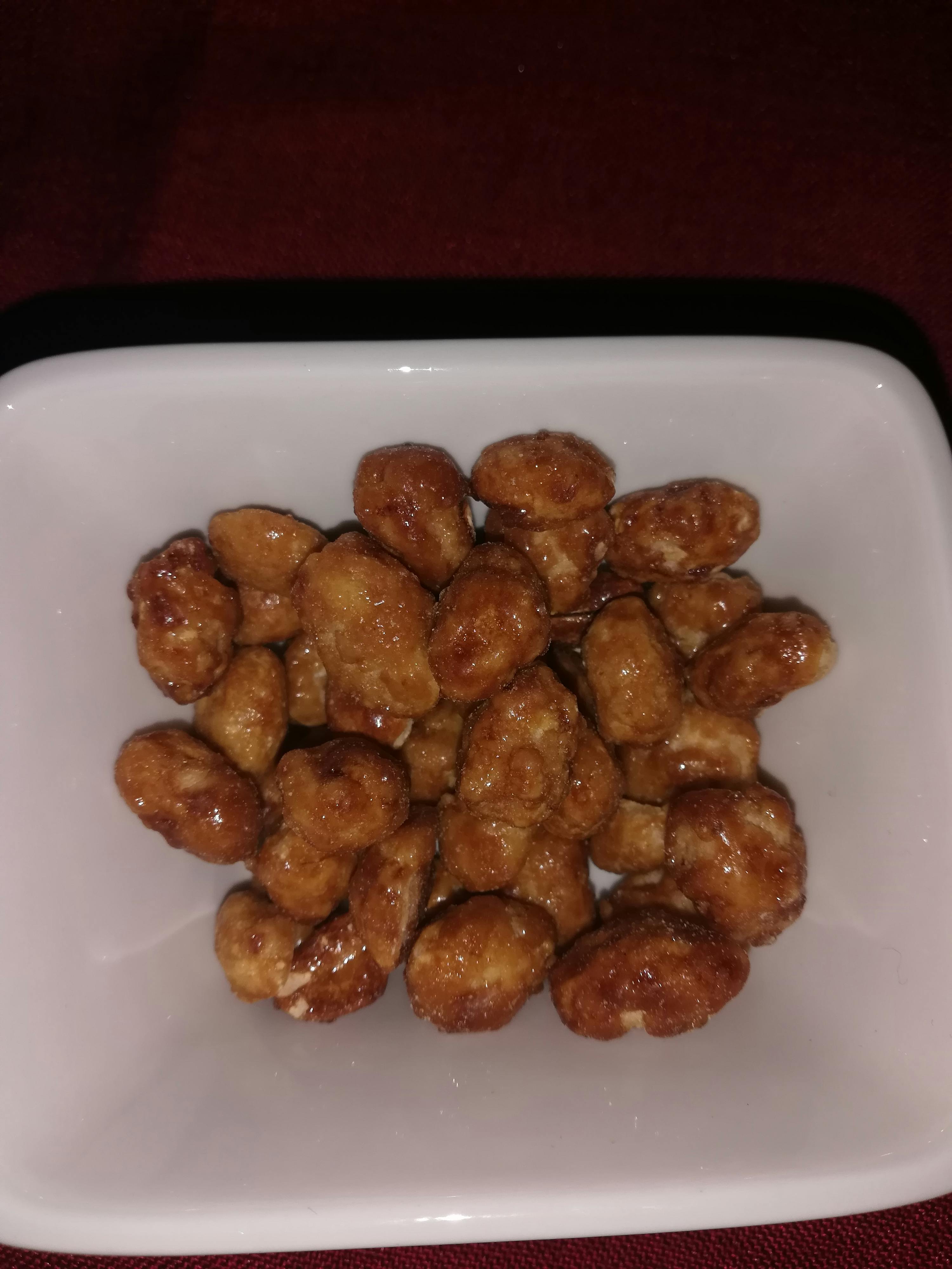 un bol blanc rempli d' amandes caramélisées sur une table