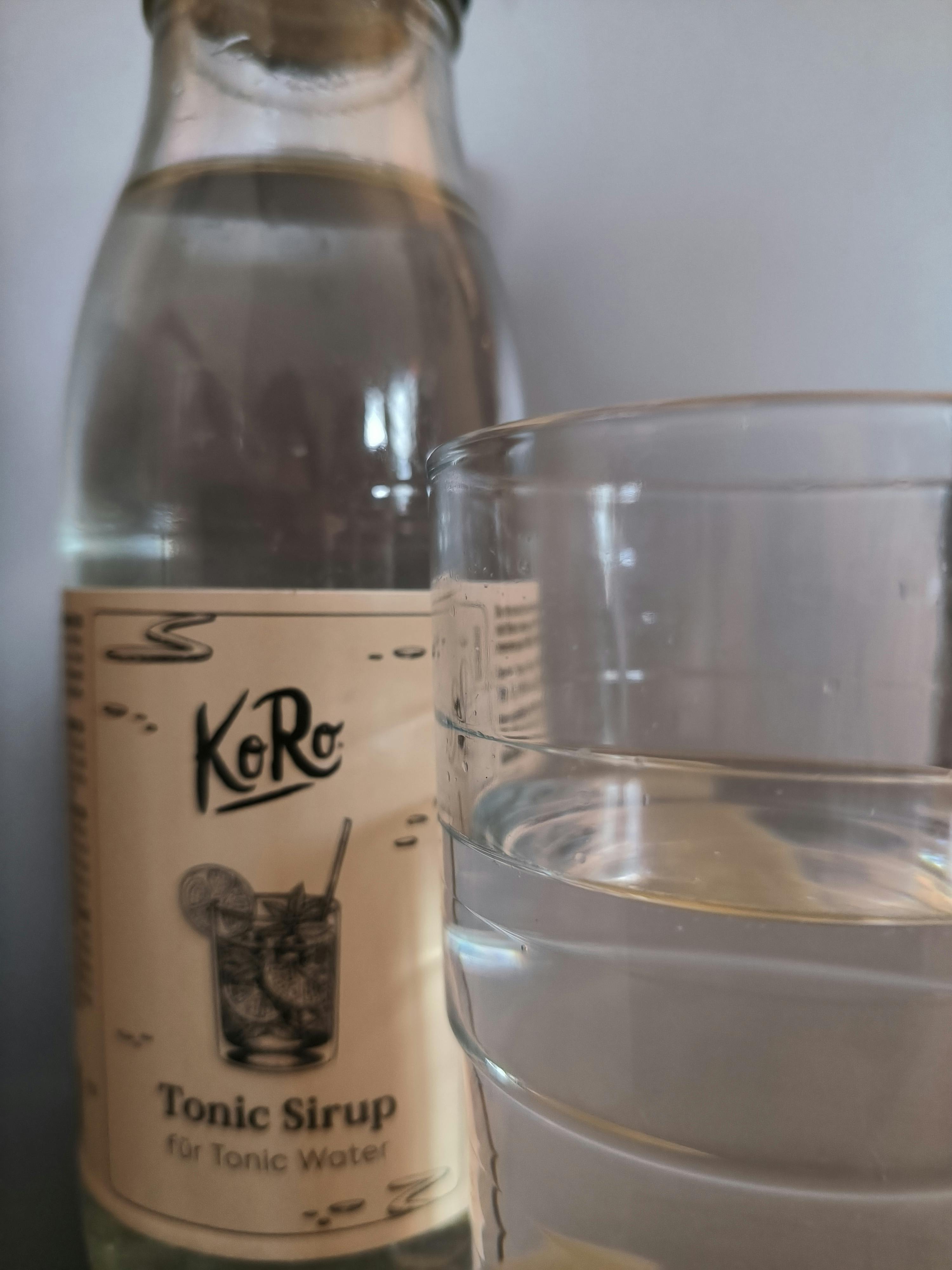 una bottiglia di tonic sirup è accanto a un bicchiere di acqua