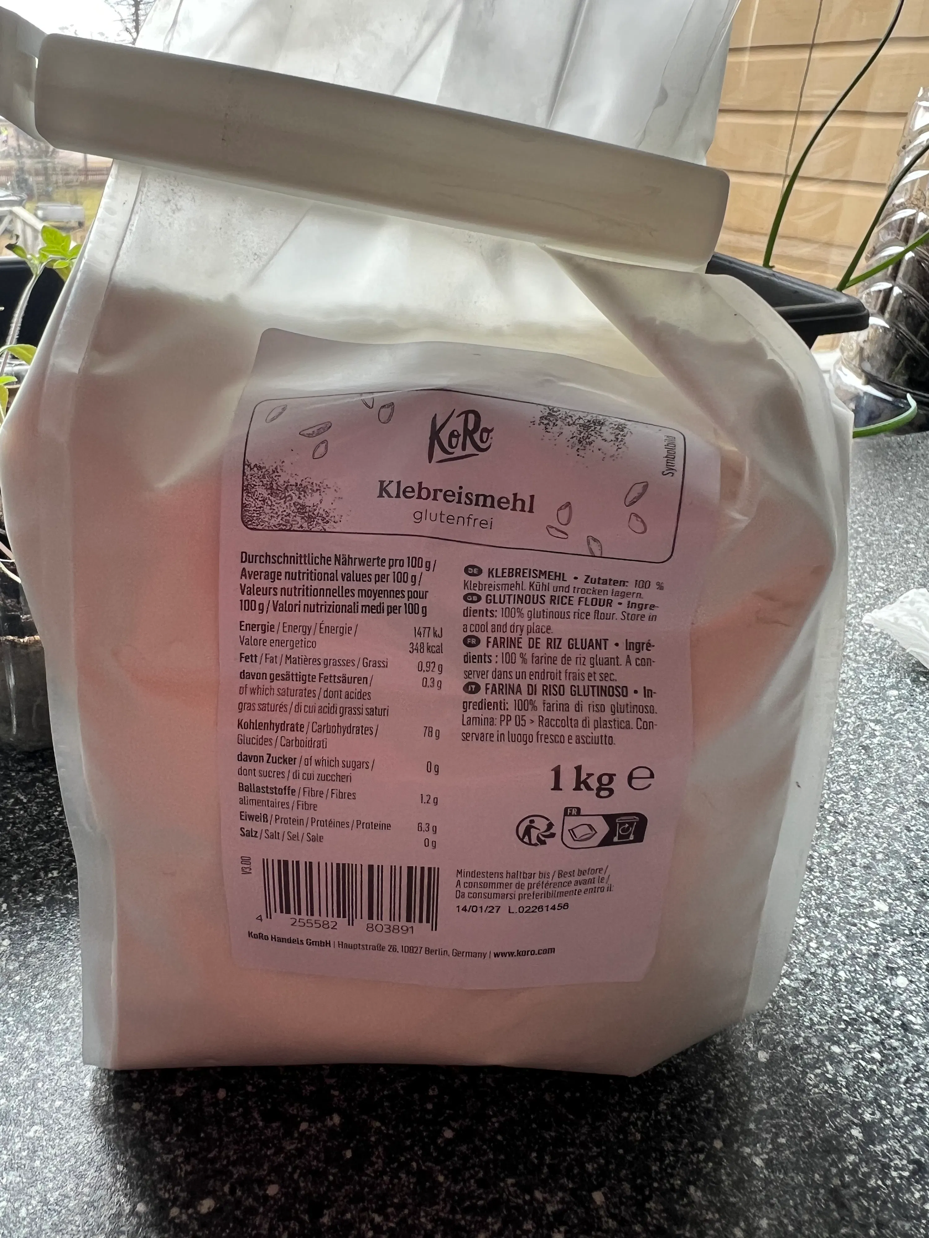 eine weiße tüte koro klebreismehl (glutenfreies reismehl) mit einem gewicht von 1 kg ist auf einer dunklen oberfläche zu sehen.