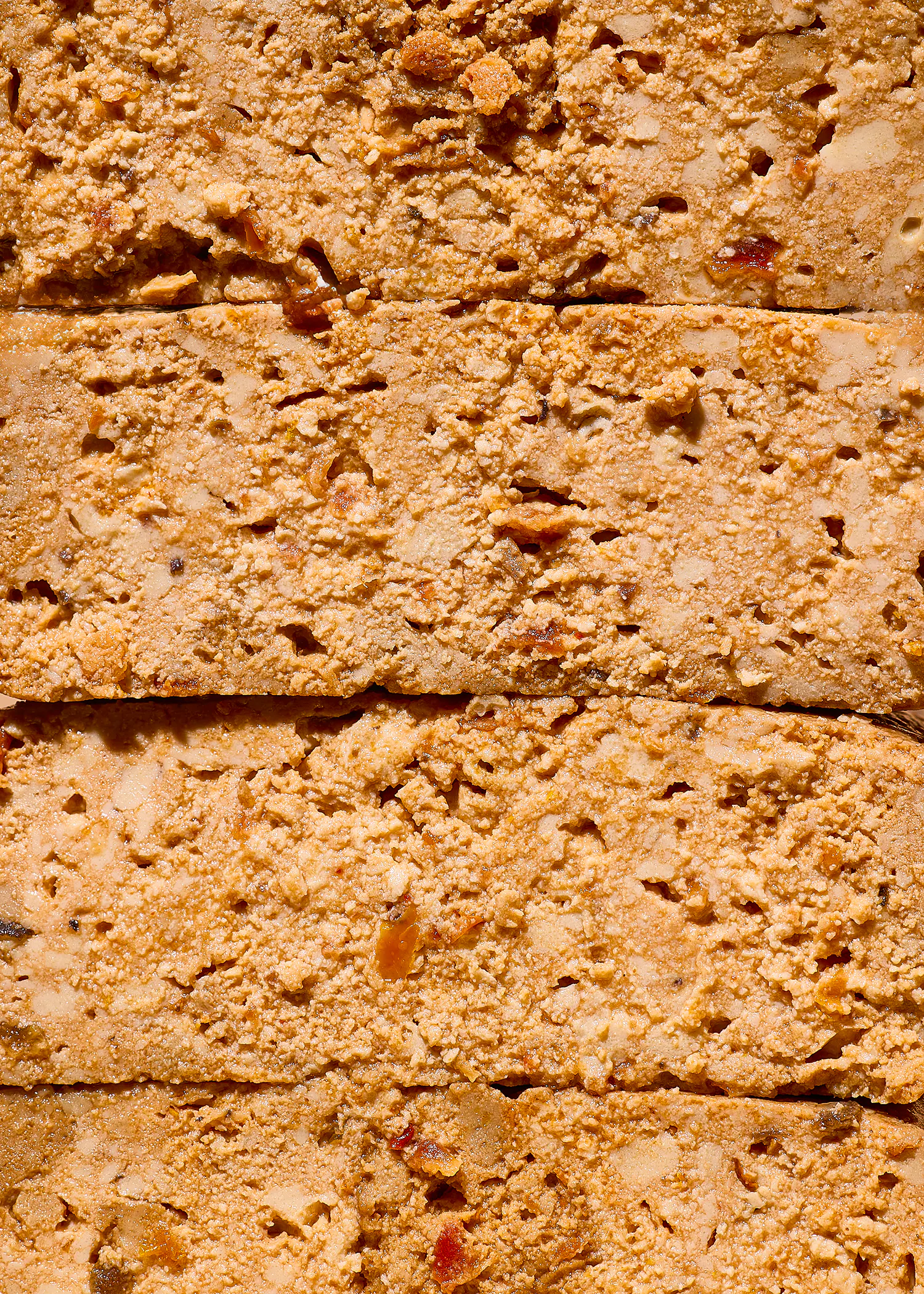 gros plan sur des barres empilées de couleur beige-brun, avec une texture granuleuse et des morceaux incrustés.