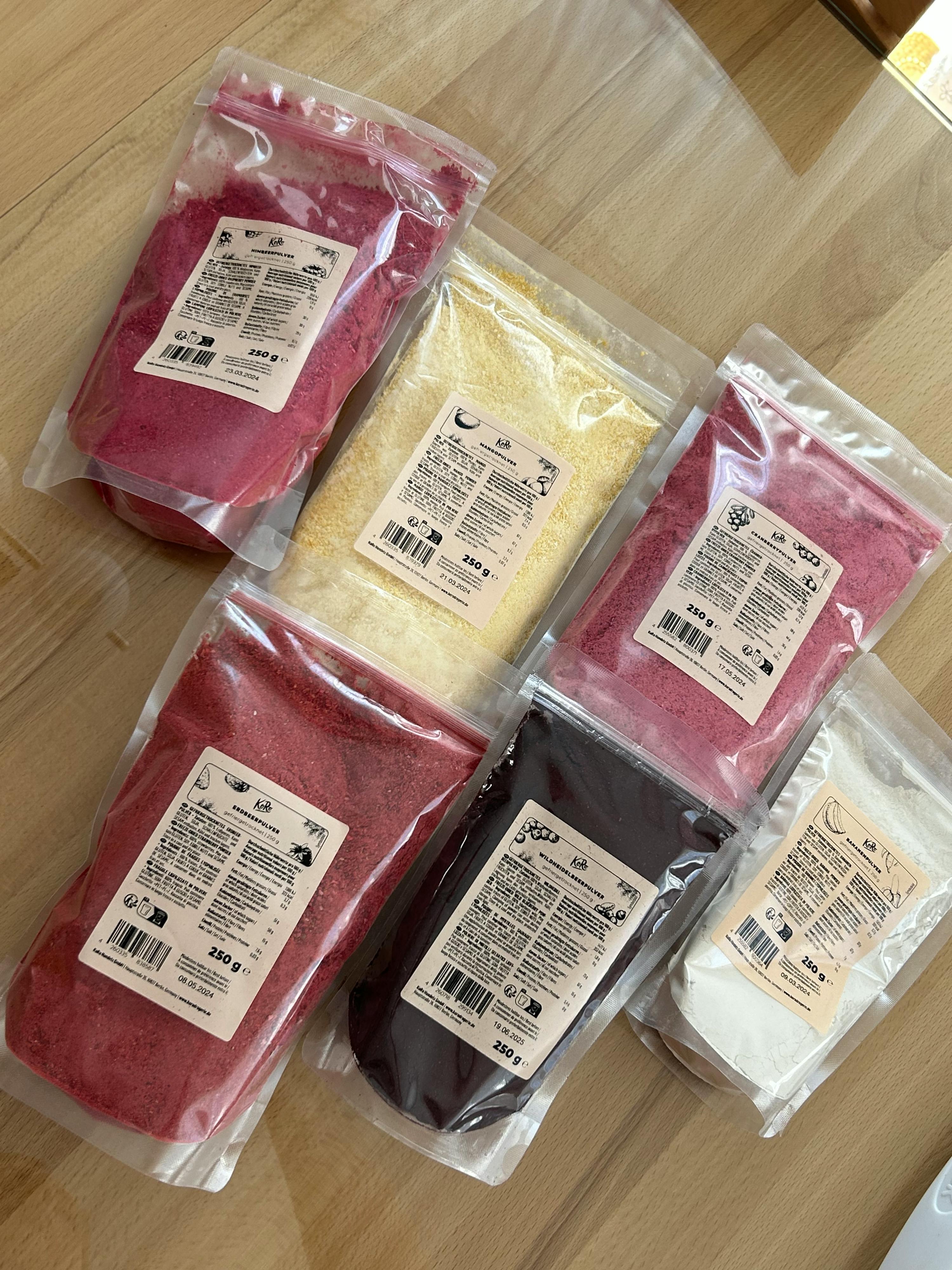 several bags of different colored powders are lined up on a table