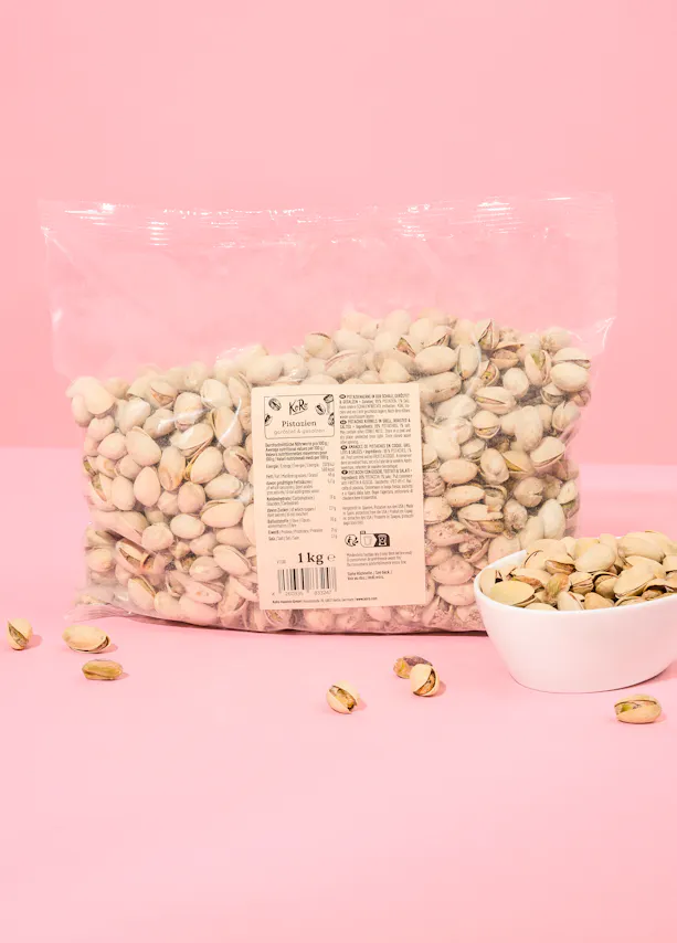 un sac de pistaches est assis sur une table rose