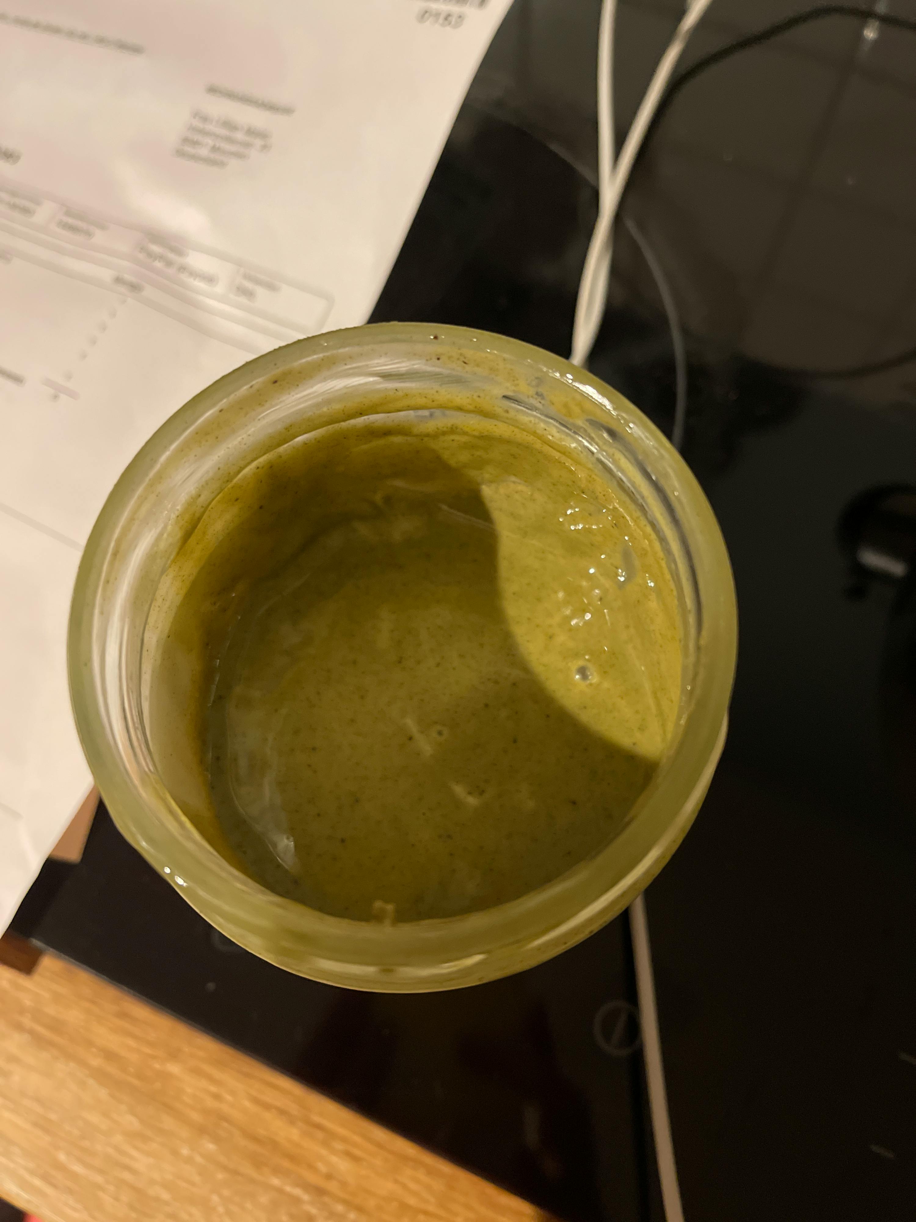 a jar of green sauce sits on a table