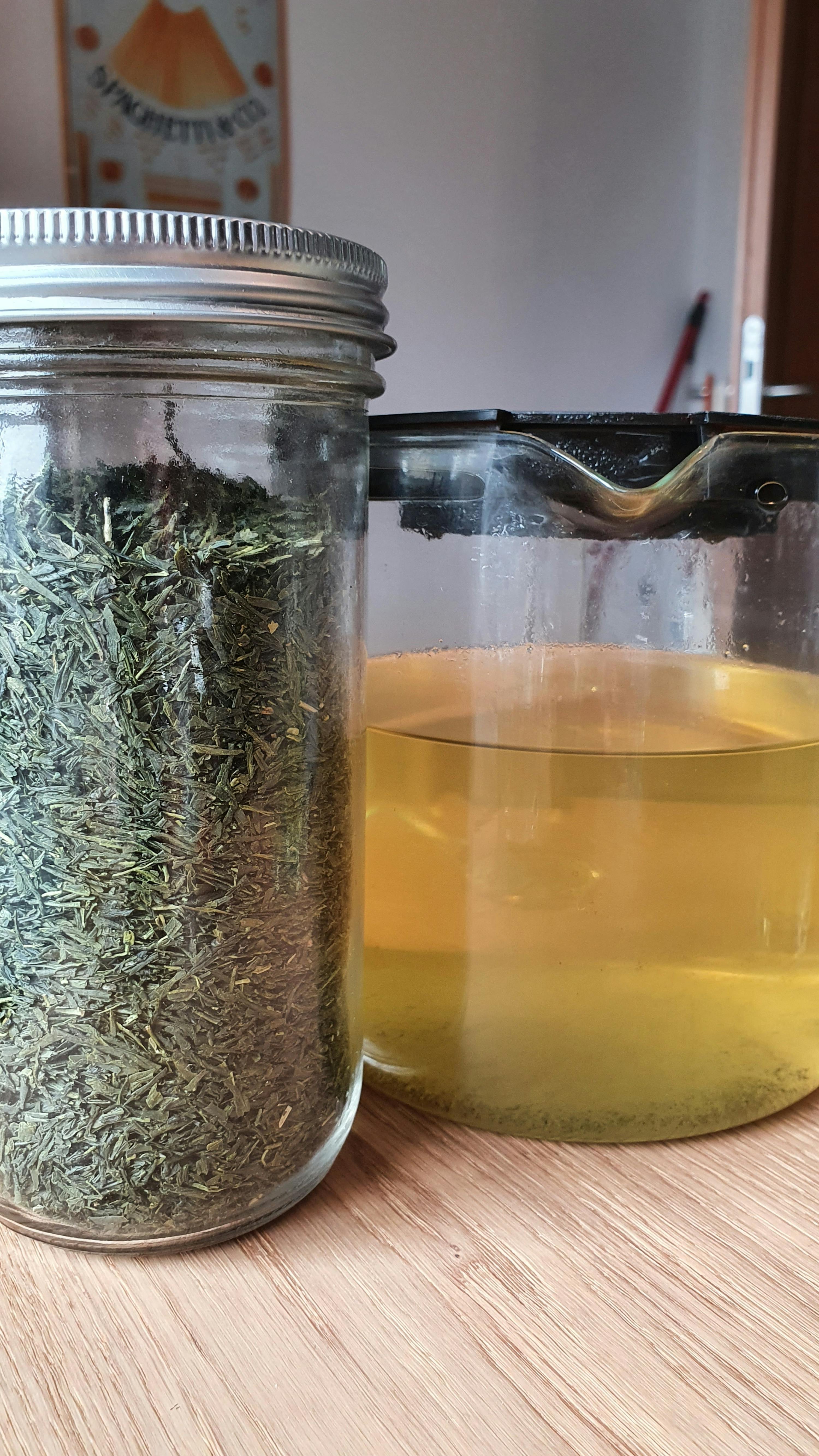 ein Glas mit grünem Tee steht neben einem Glas mit Wasser