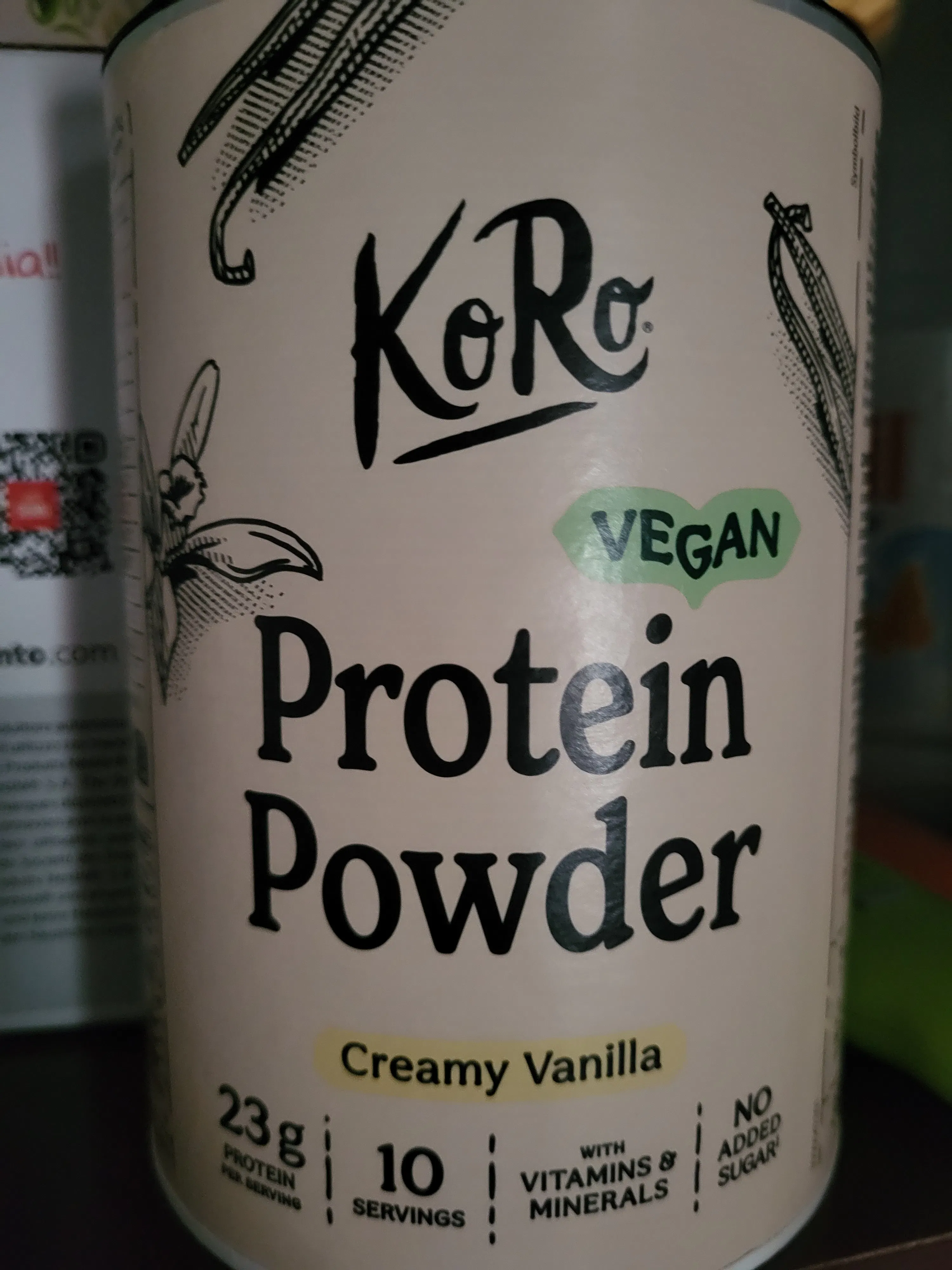 a white and green container of koro vegan creamy vanilla protein powder, showing 23g protein per serving, 10 servings, no added sugar, and with vitamins and minerals.