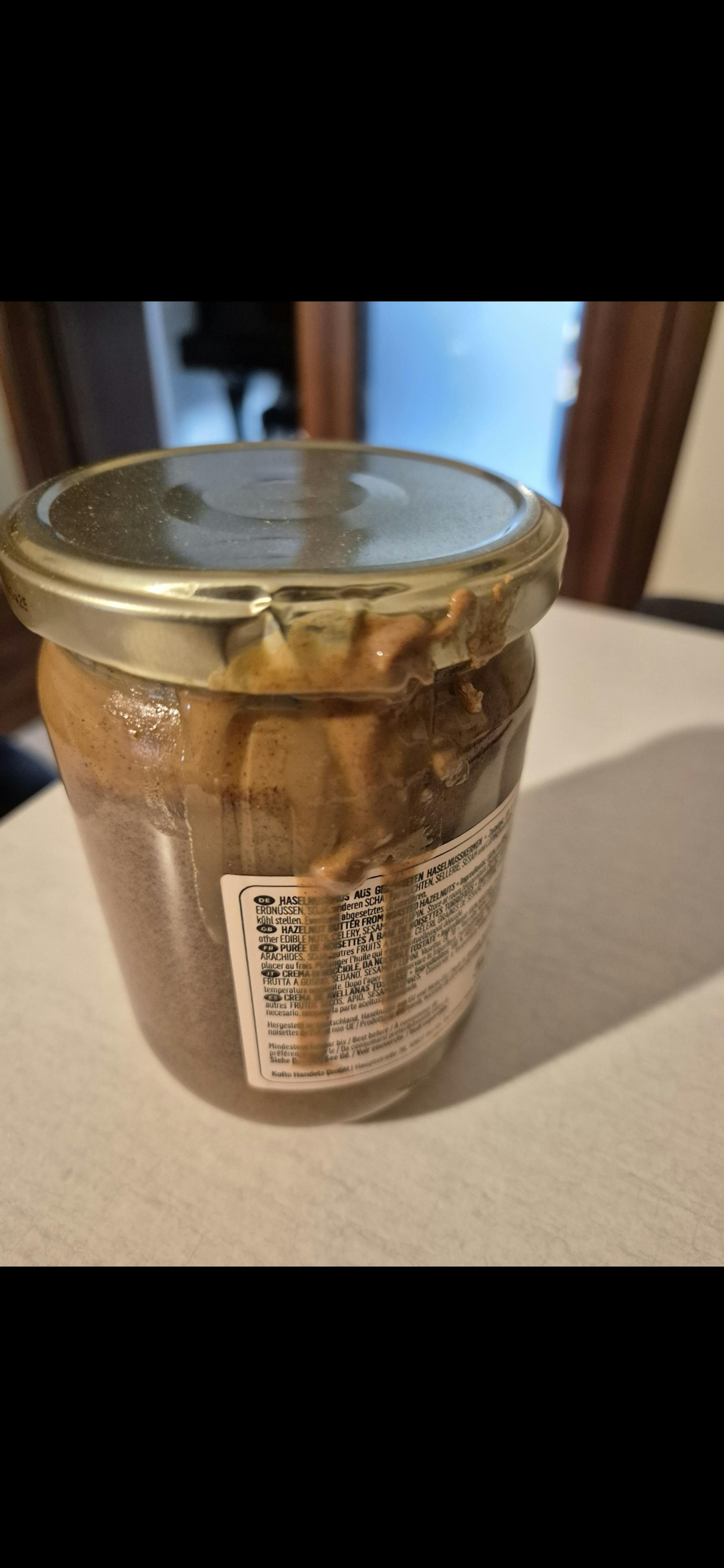 a jar of peanut butter sits on a white table