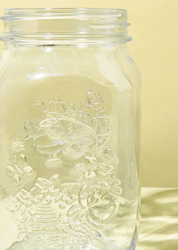 ein leeres Glasgefäß mit einem Muster darauf steht auf einem Tisch