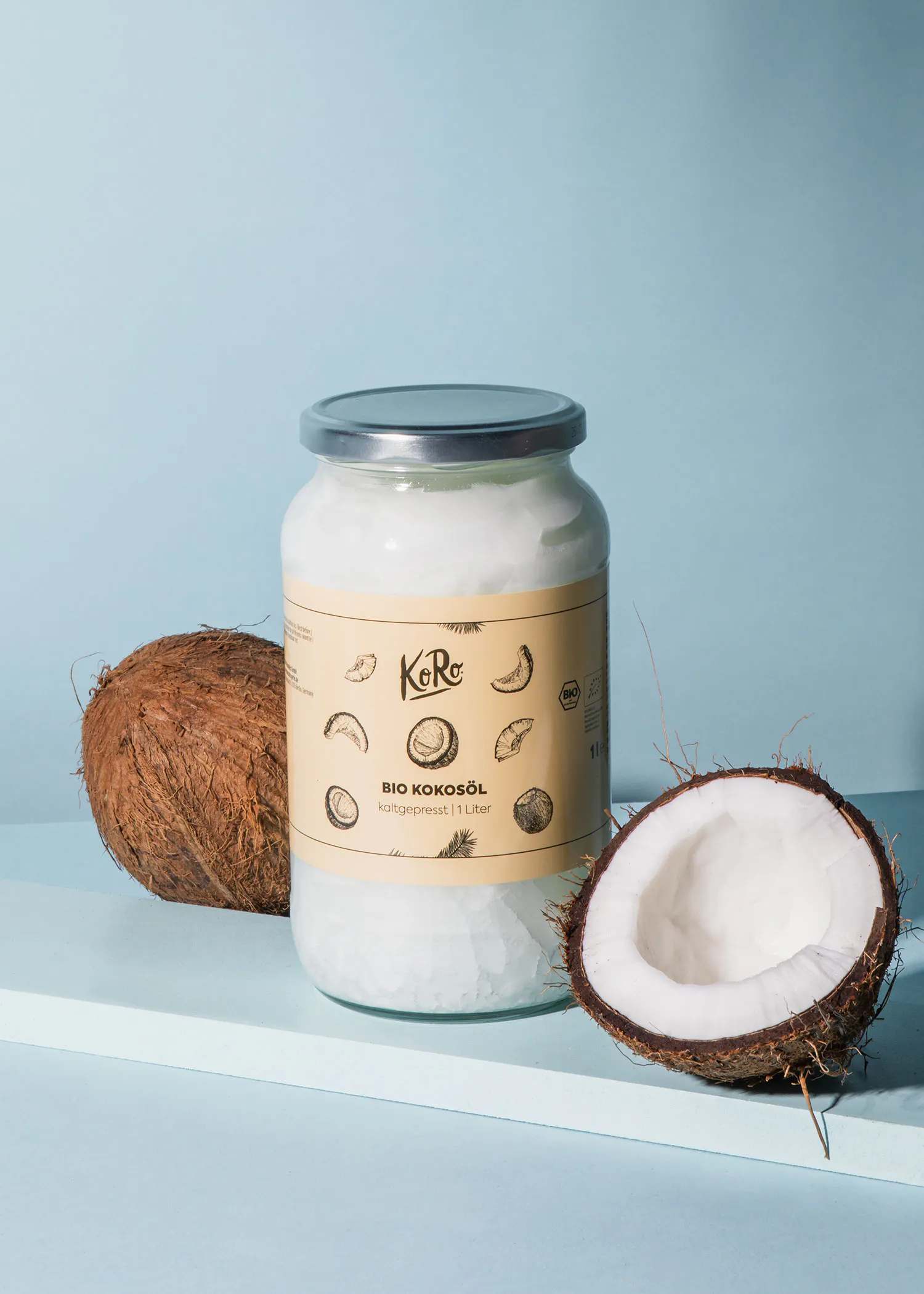 une bouteille d' huile de noix de coco bio avec une noix de coco posée à côté