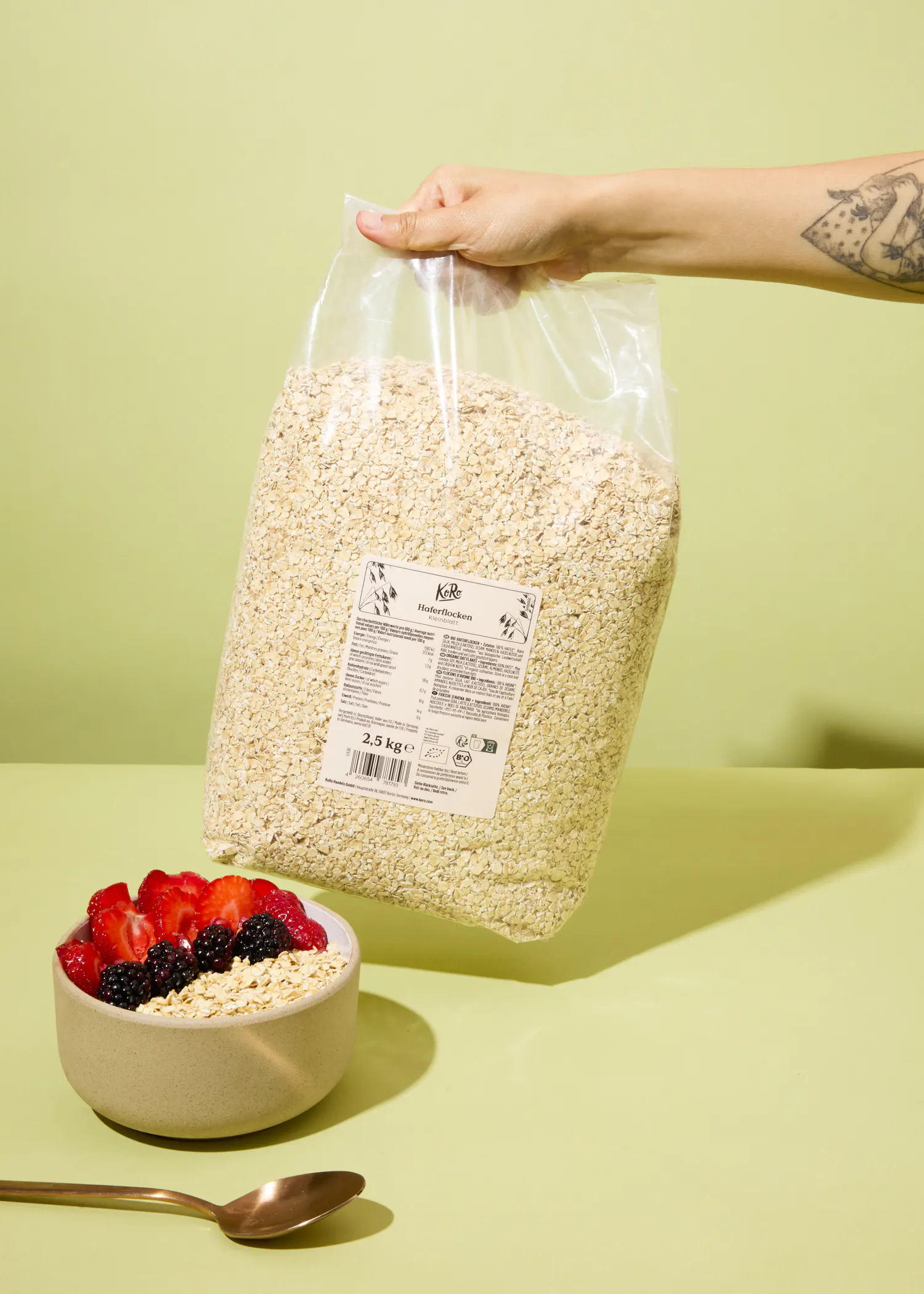 une personne tient un sac de flocons d' avoine à côté d' un bol de flocons d' avoine avec des baies
