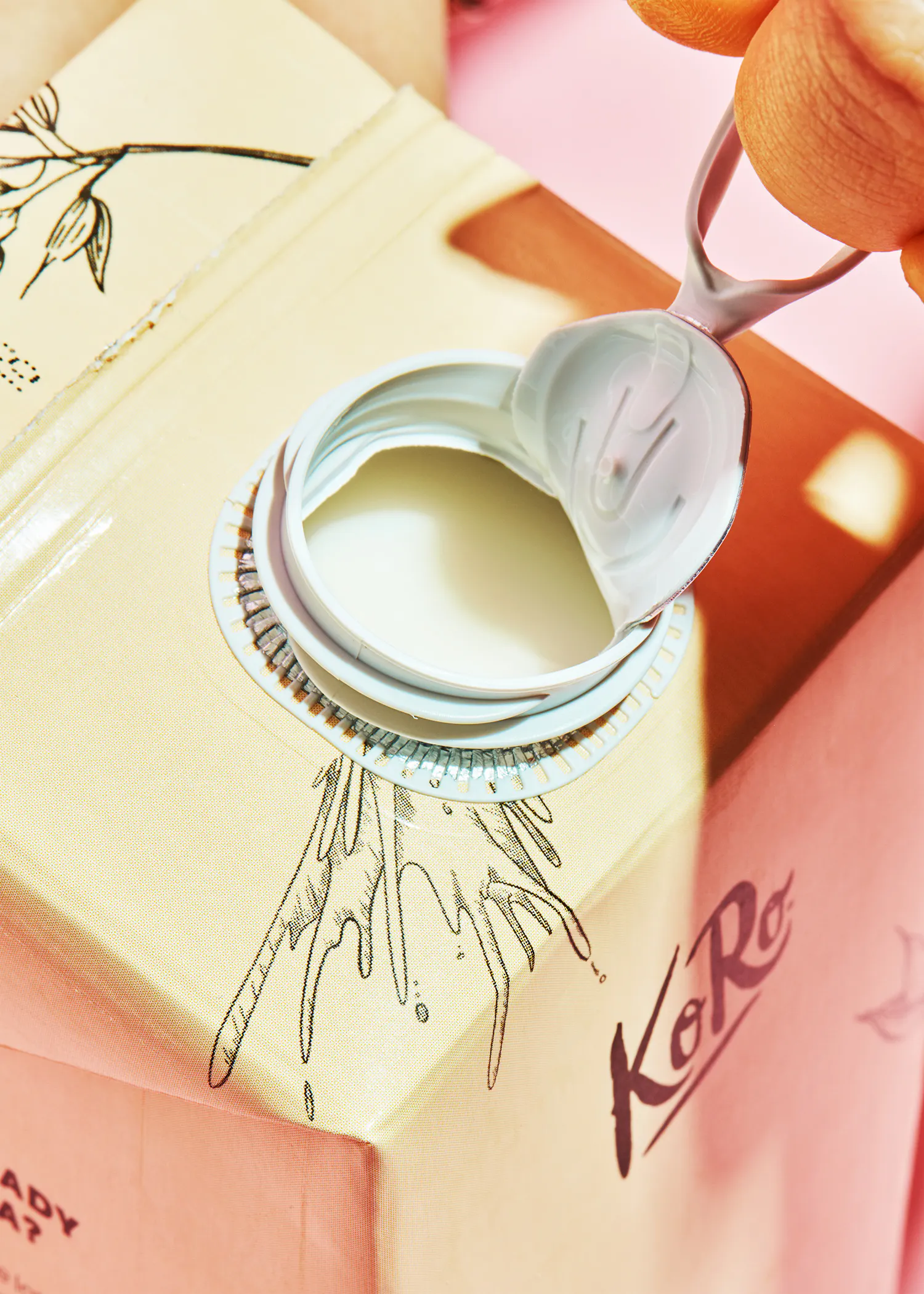 une personne ouvre une boîte de koré avec une cuillère