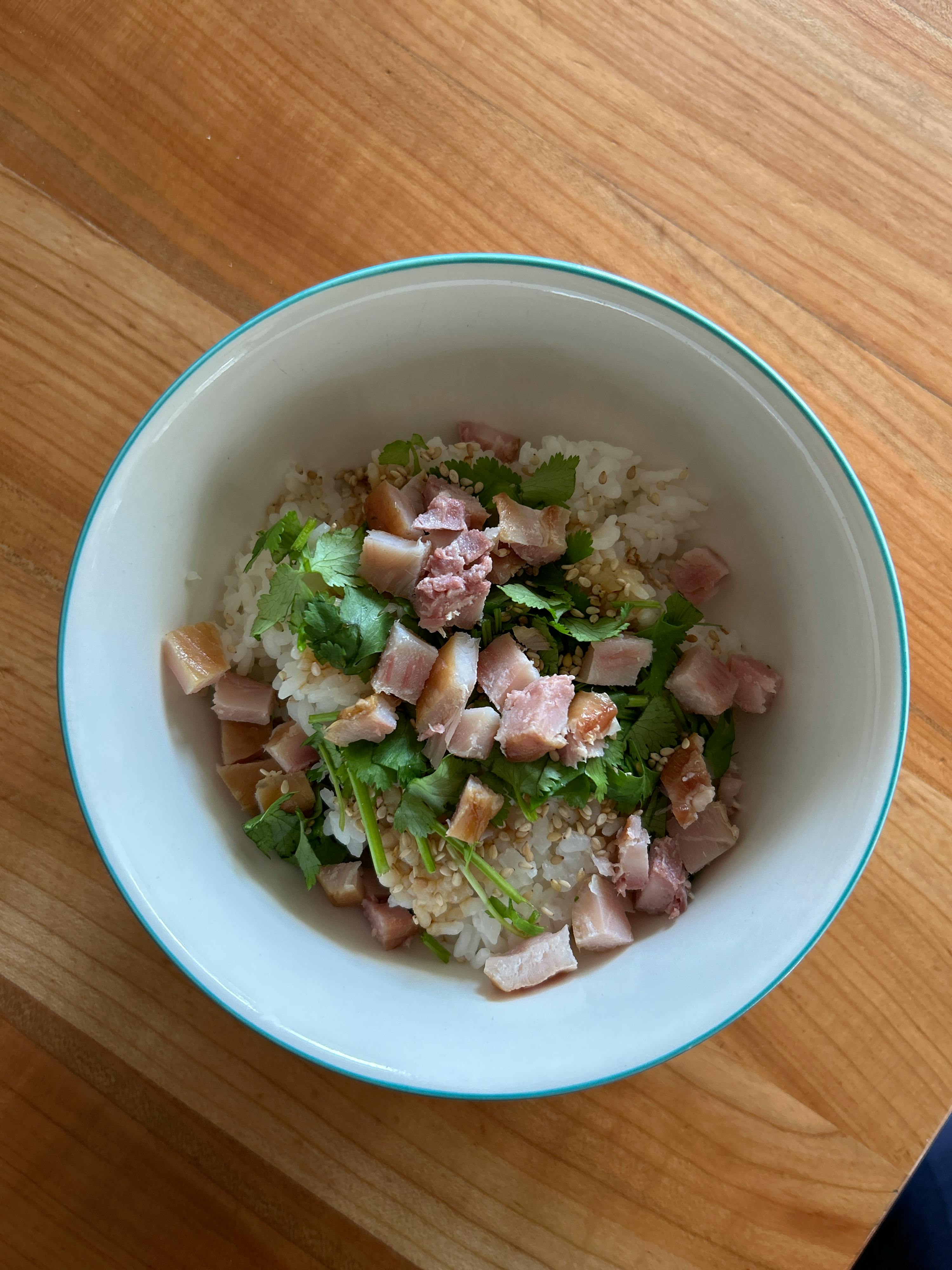 a white bowl filled with rice and meat on a wooden table