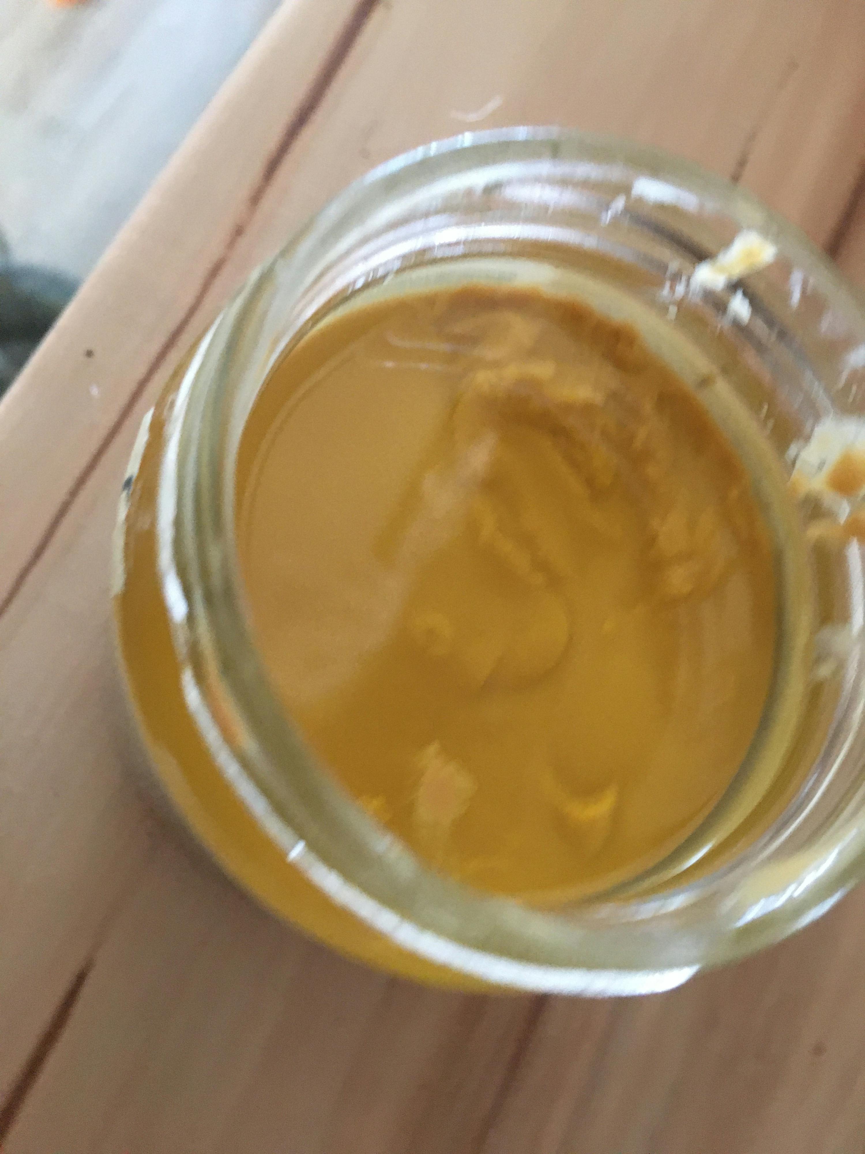 ein Glas mit gelber Flüssigkeit darin steht auf einem Holztisch