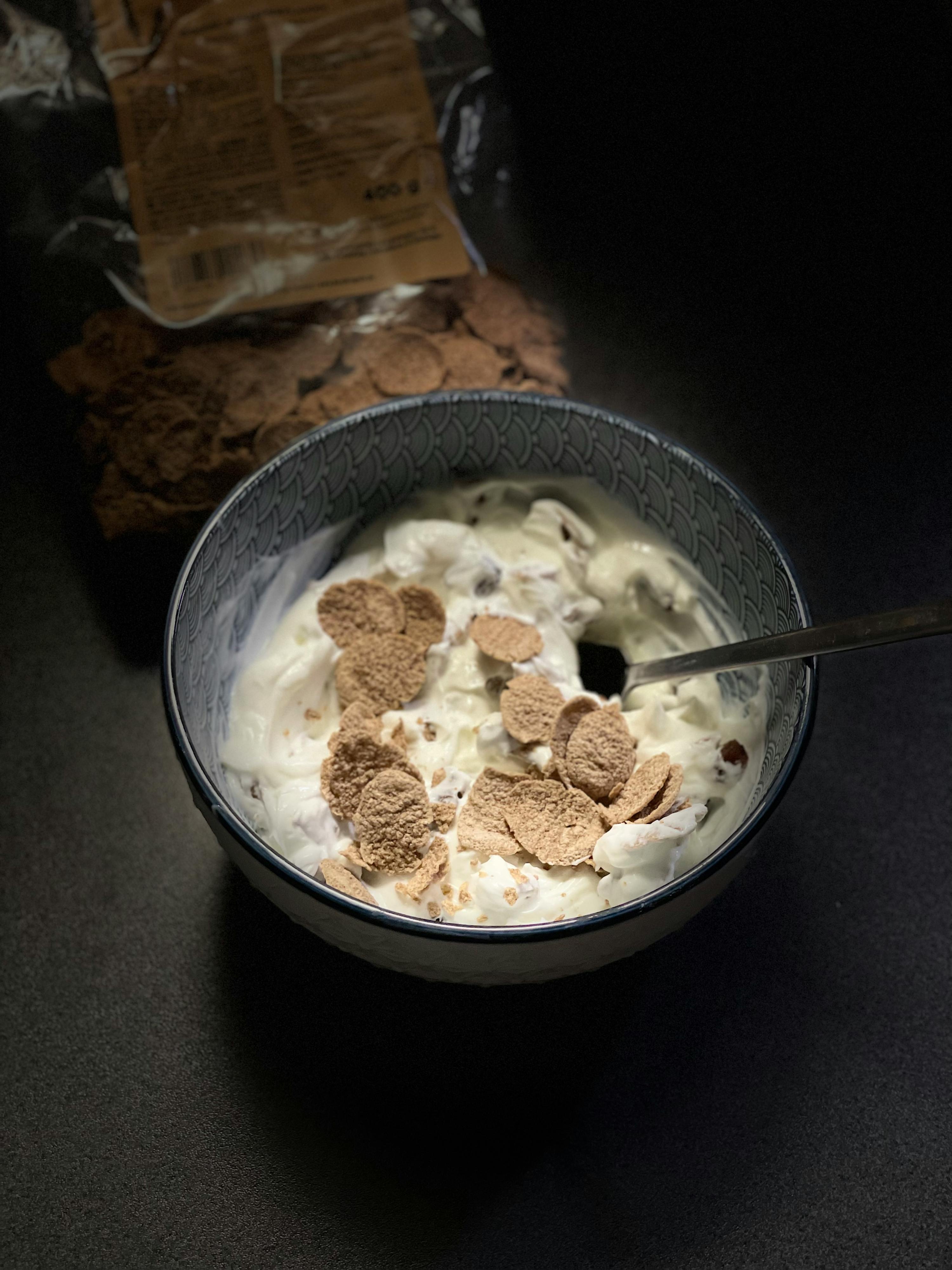 eine Schüssel Joghurt mit Maisflocken und einem Löffel