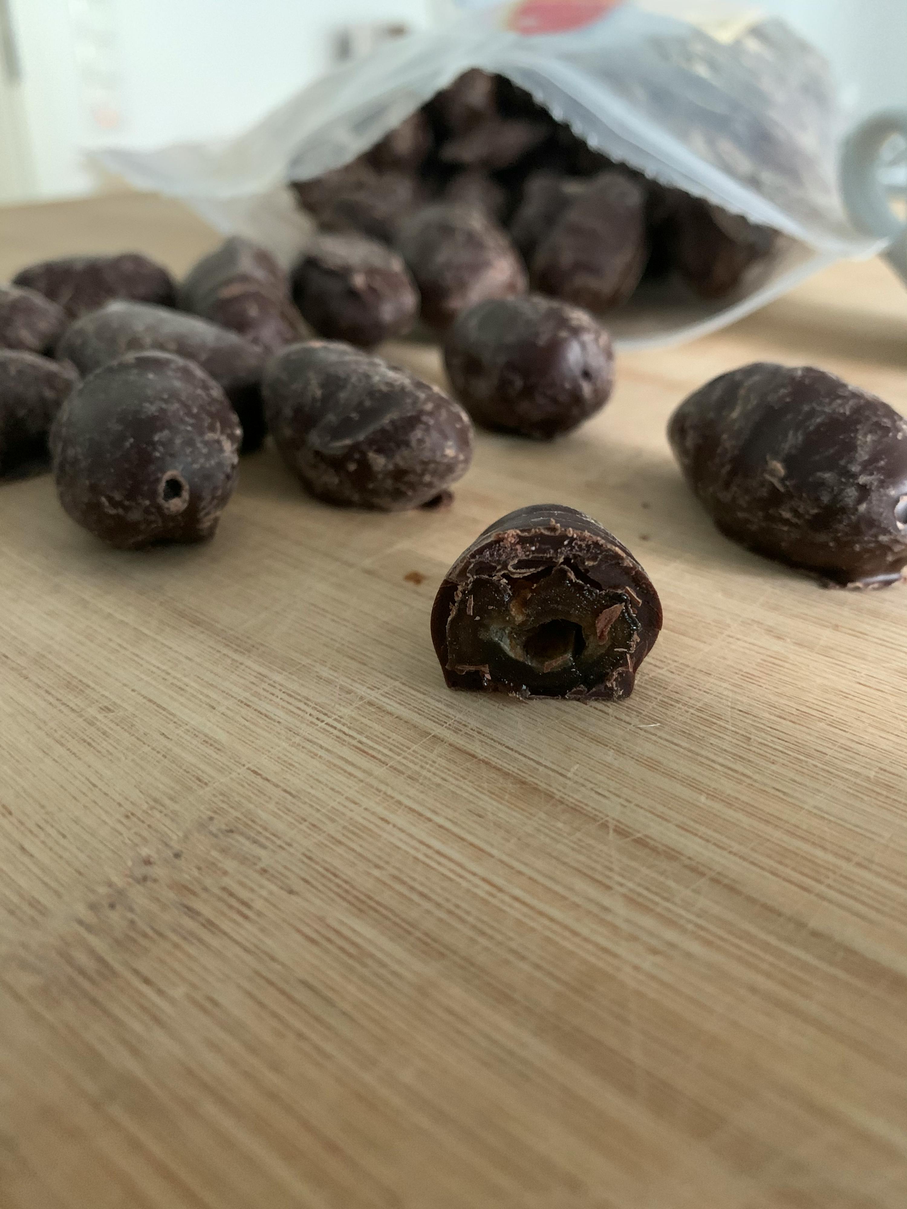 un pezzo di cioccolato è seduto su un tagliere di legno accanto a un sacchetto di cioccolato