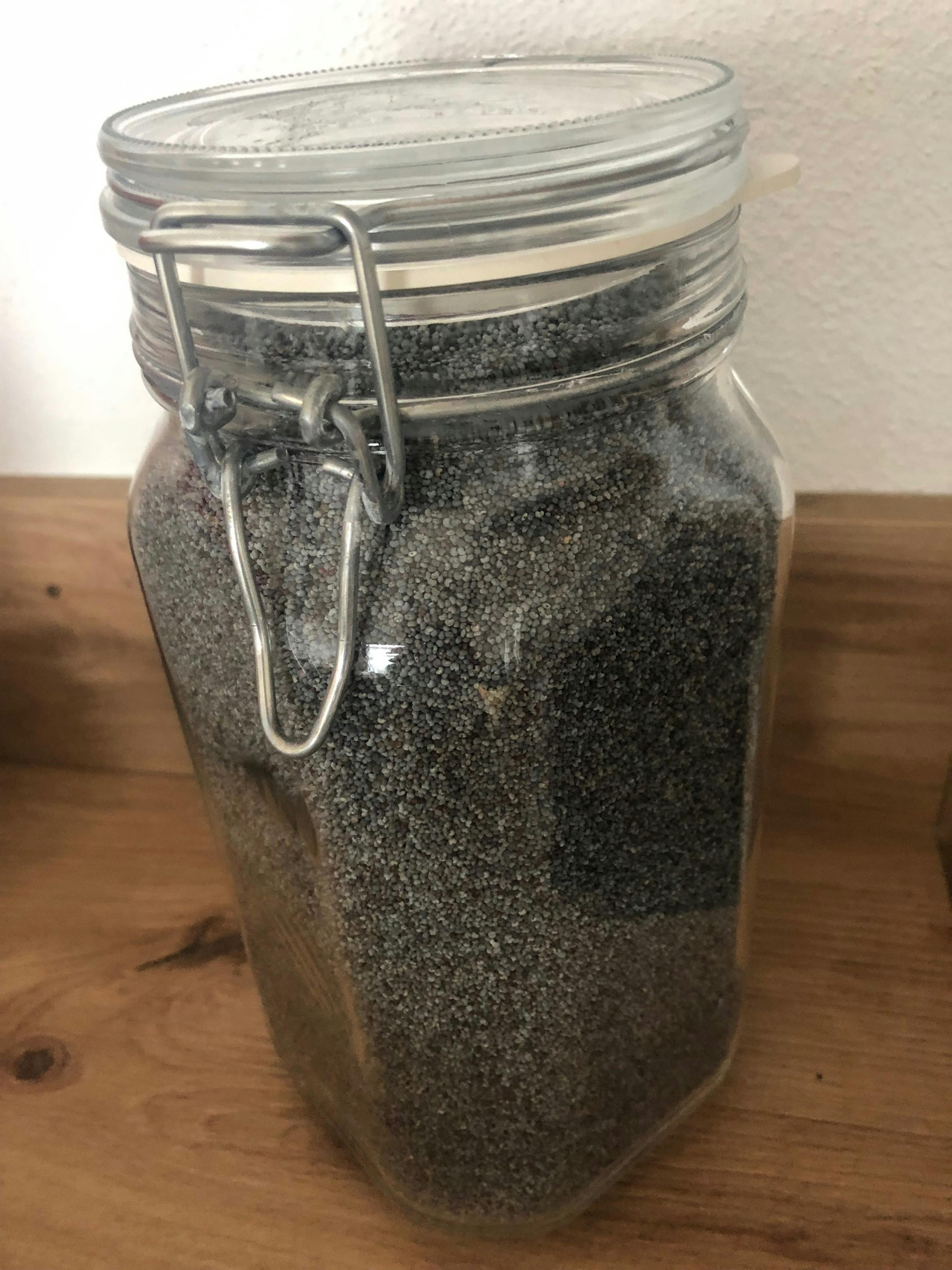 a glass jar filled with a gray substance on a wooden surface