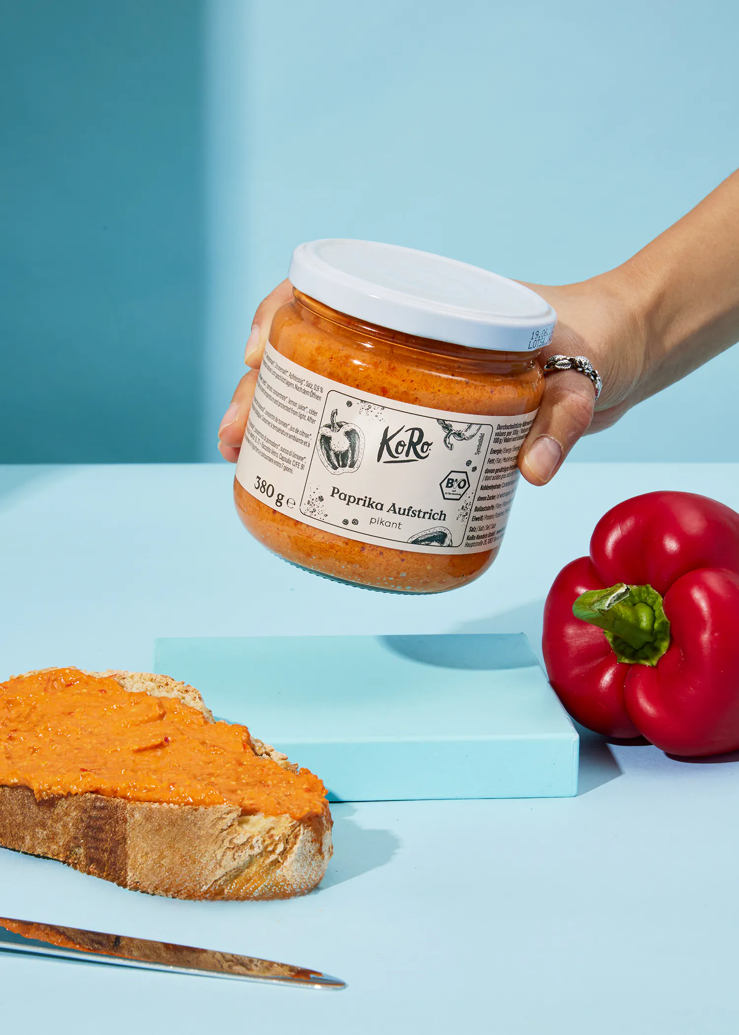 eine Person hält ein Glas mit paprika aufstrich in der Hand