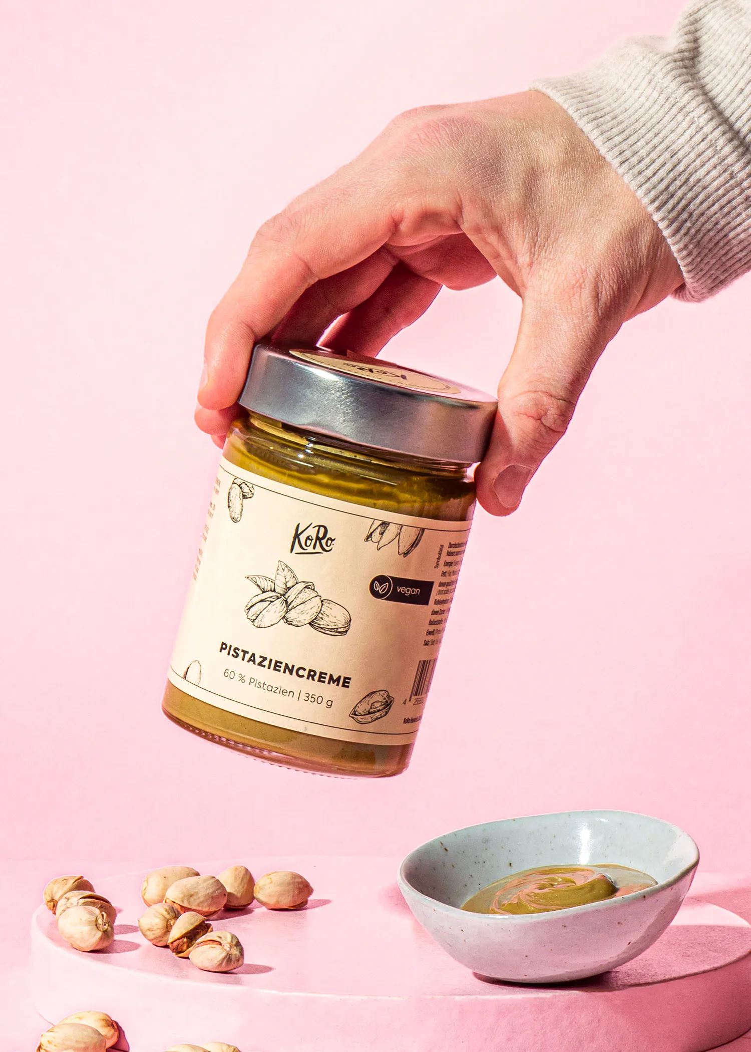une personne tient un pot de pistaziencreme à la main