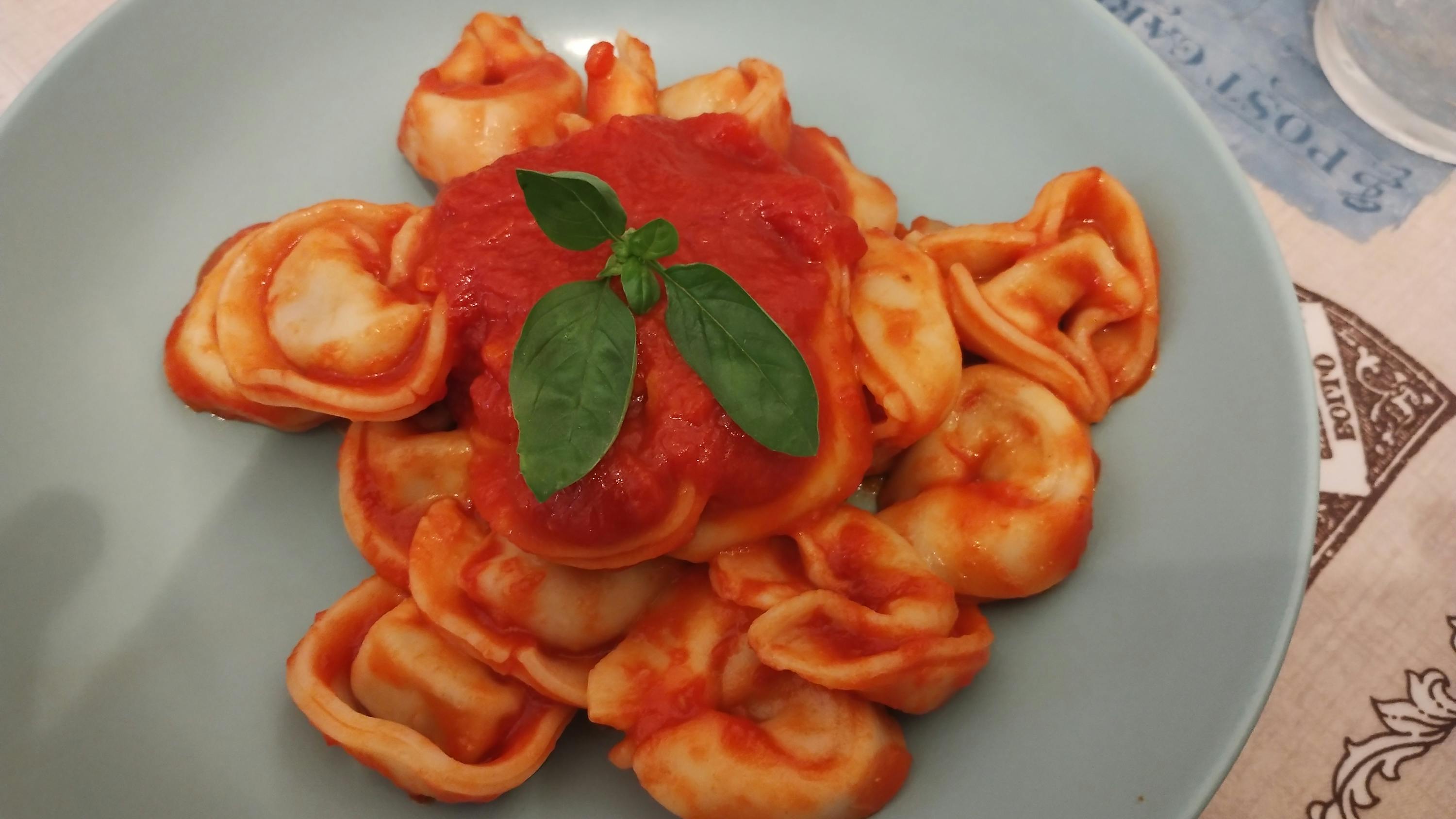 a plate of pasta with tomato sauce and basil on top