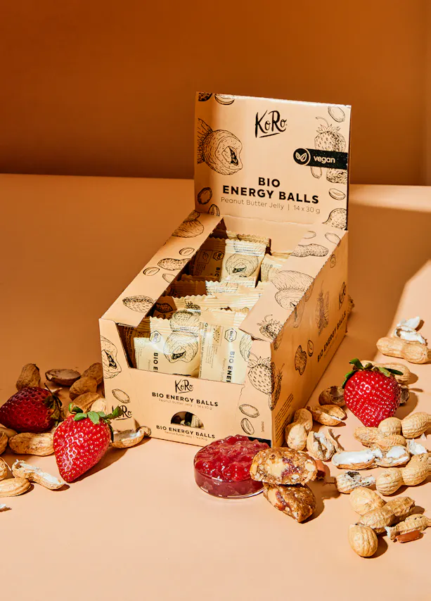 eine Schachtel Bio-Energiekugeln mit Erdbeeren und Erdnüssen darauf