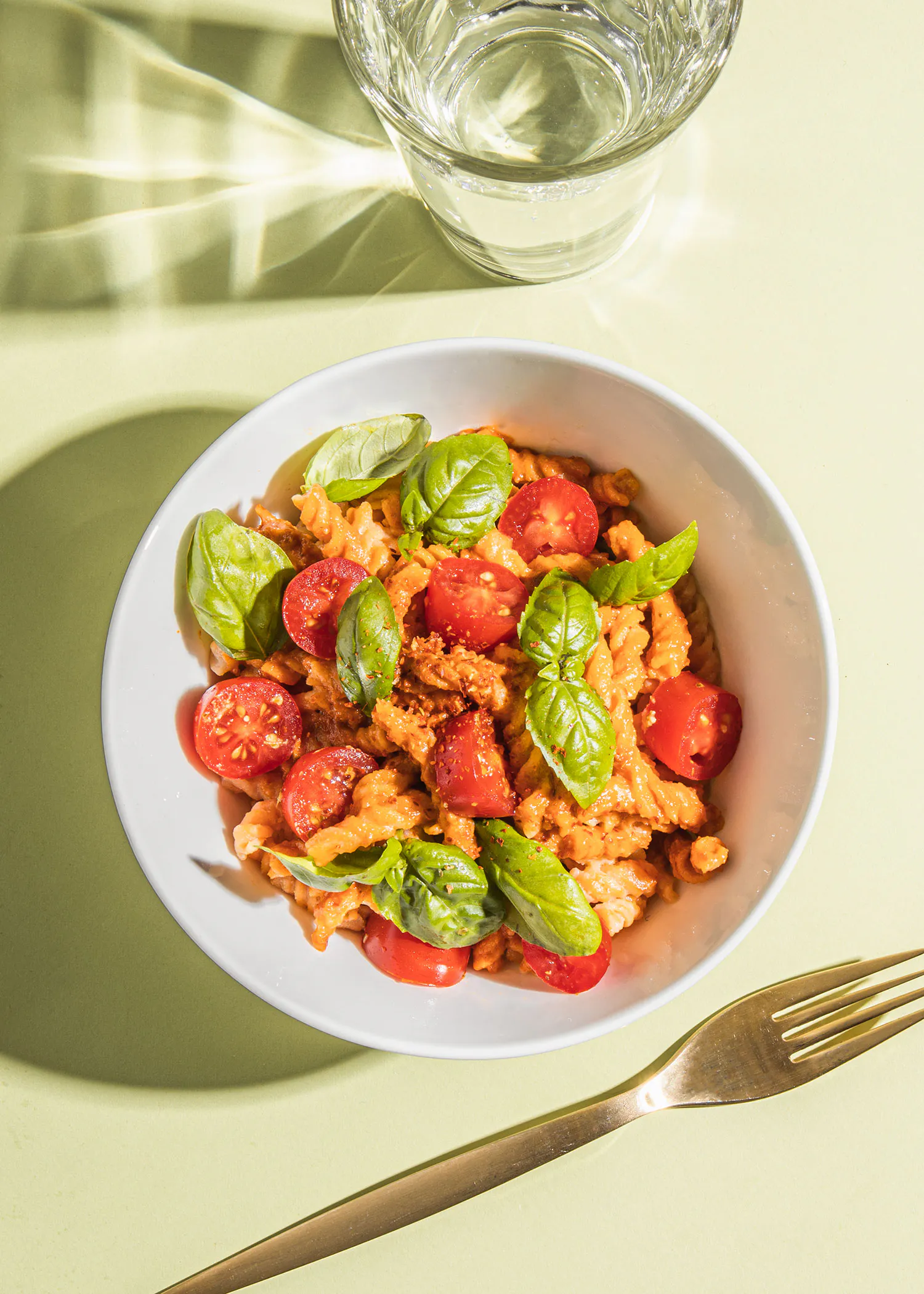 un bol de pâtes avec des tomates et du basilic