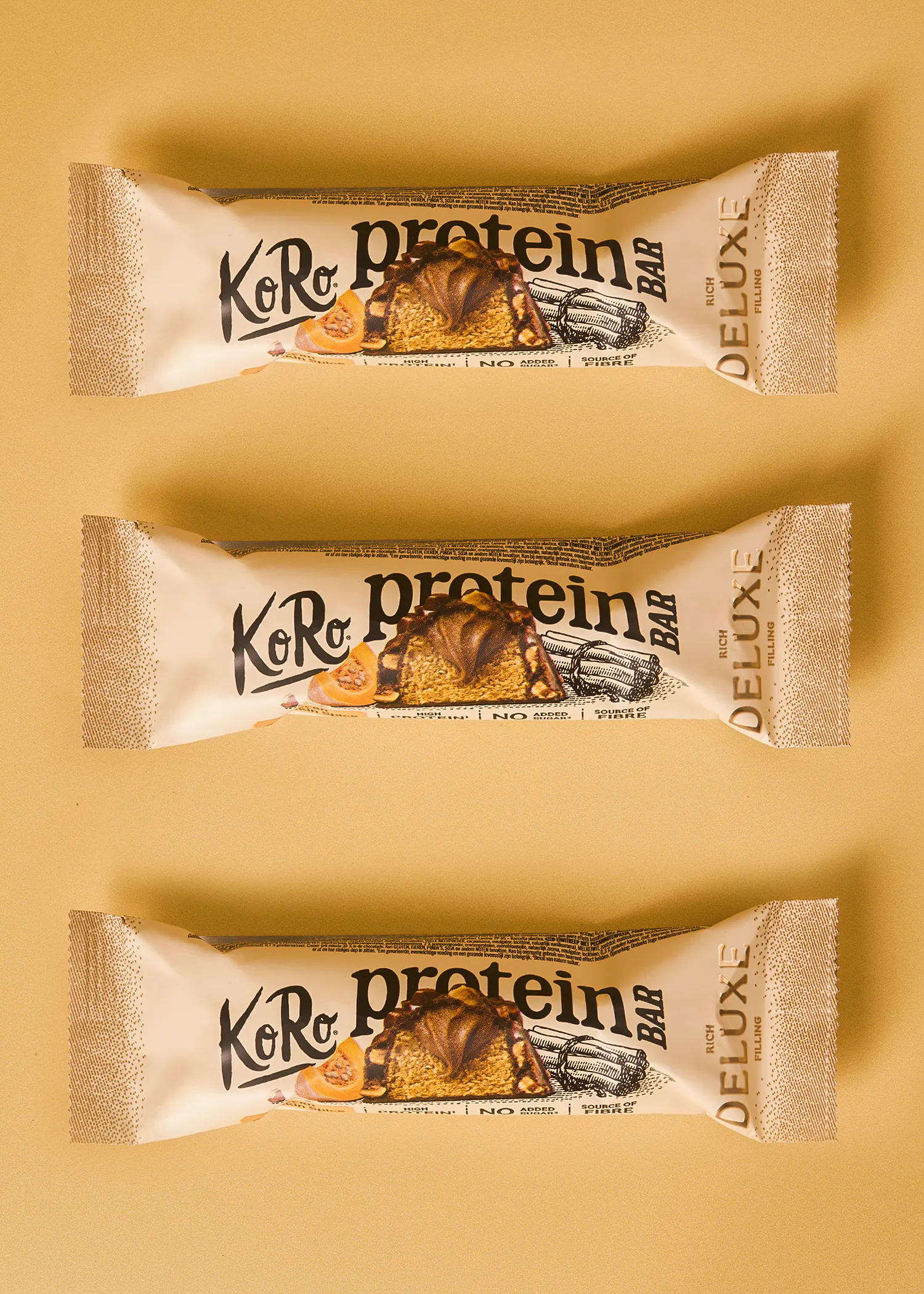three koro protein bars with a rich filling are arranged horizontally against a solid light brown background.
