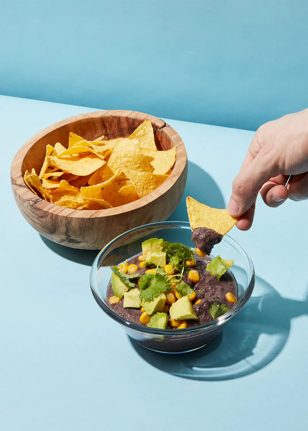 une personne plonge un crouton dans un bol de salsa