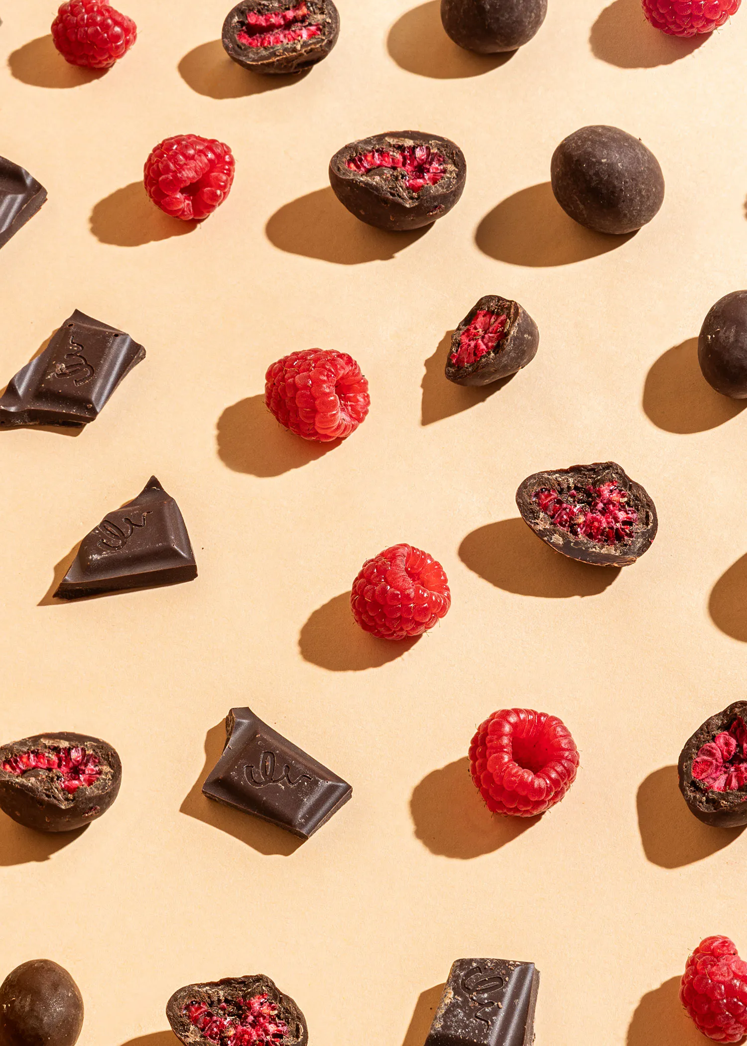 a row of chocolates and raspberries on a beige surface