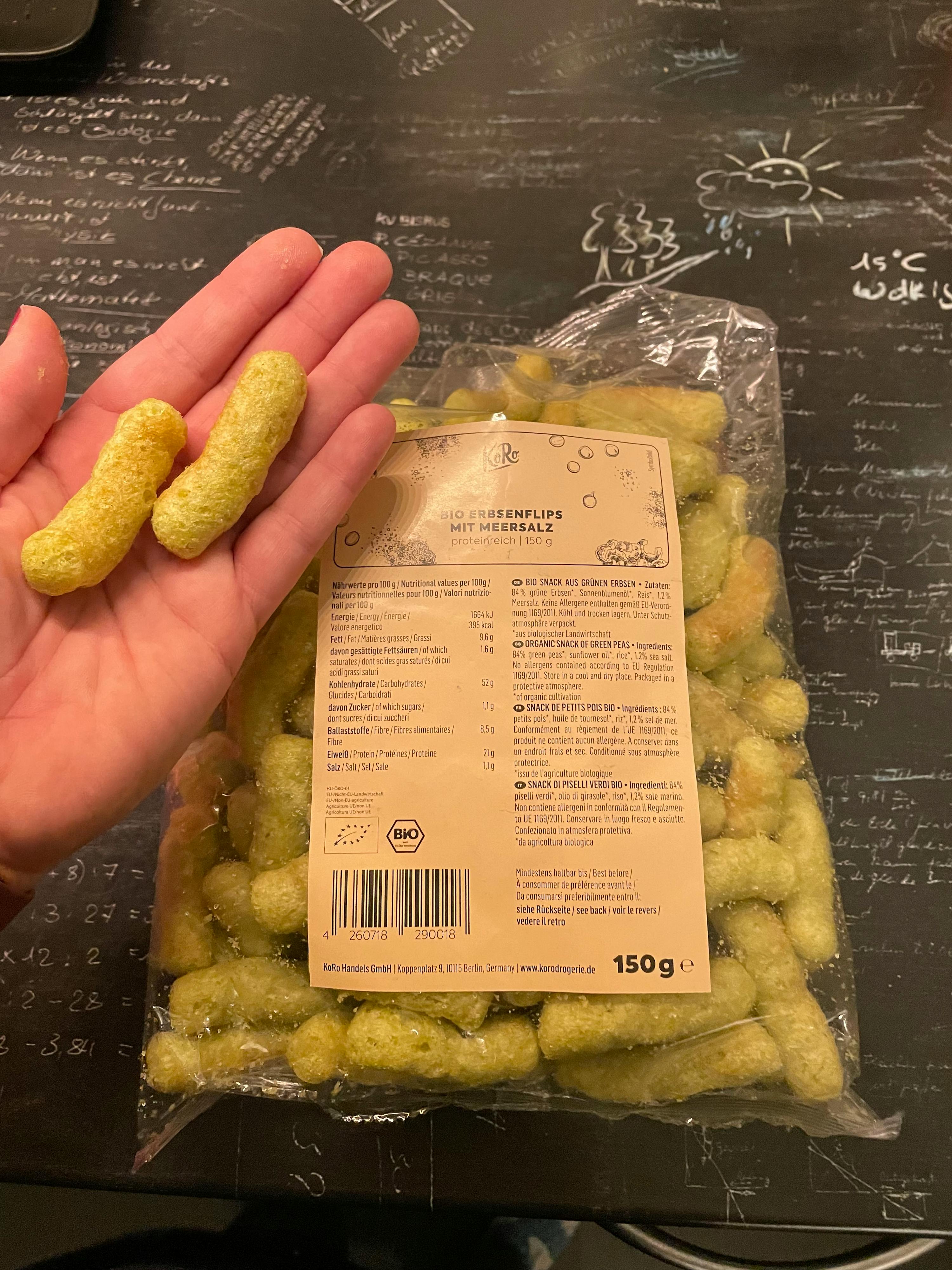 eine Person hält einen Plastikbeutel mit grünen Chips in der Hand