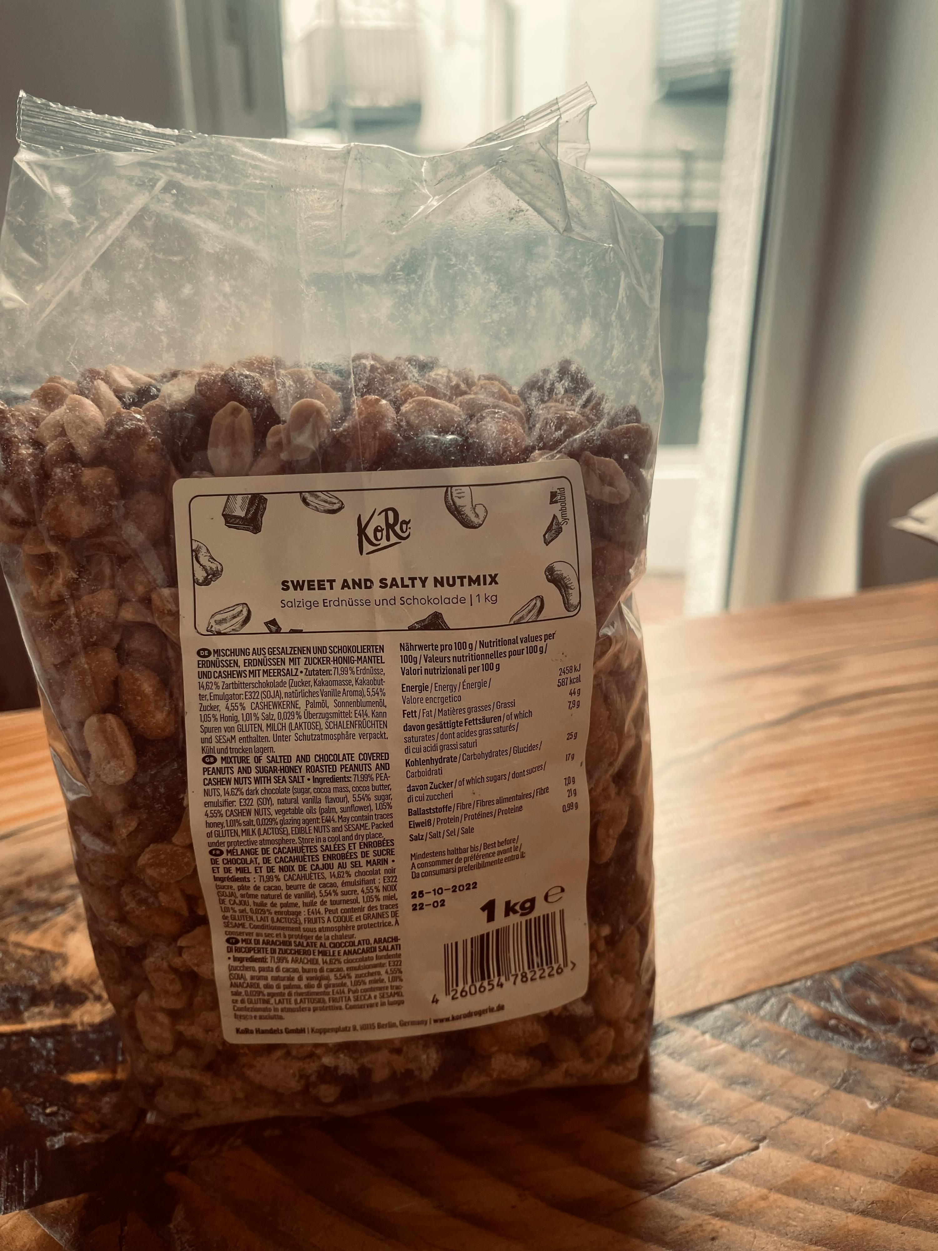 eine Tüte süßer und salziger Nussmischung steht auf einem Holztisch