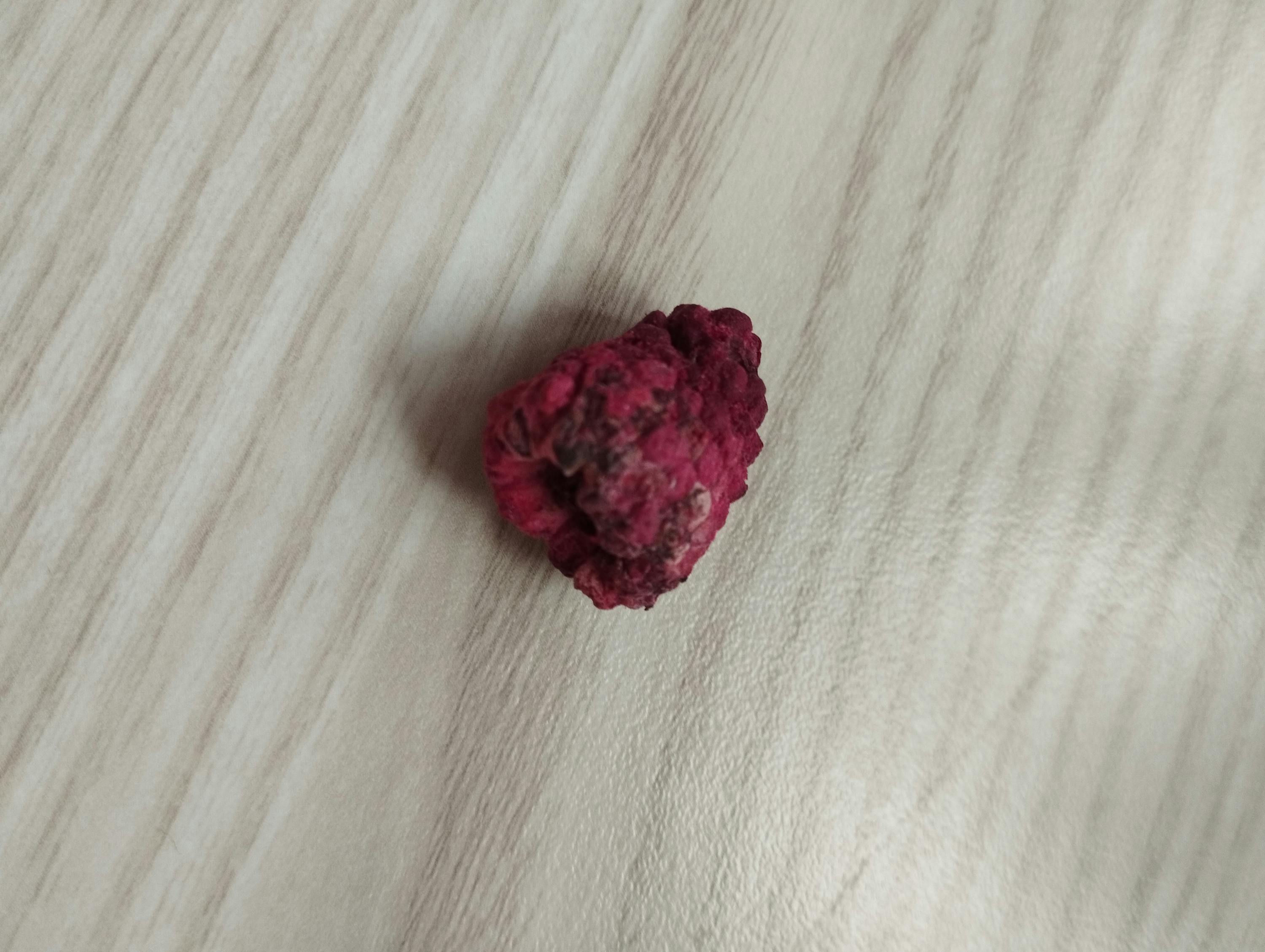 una pietra rossa è seduta su un tavolo di legno